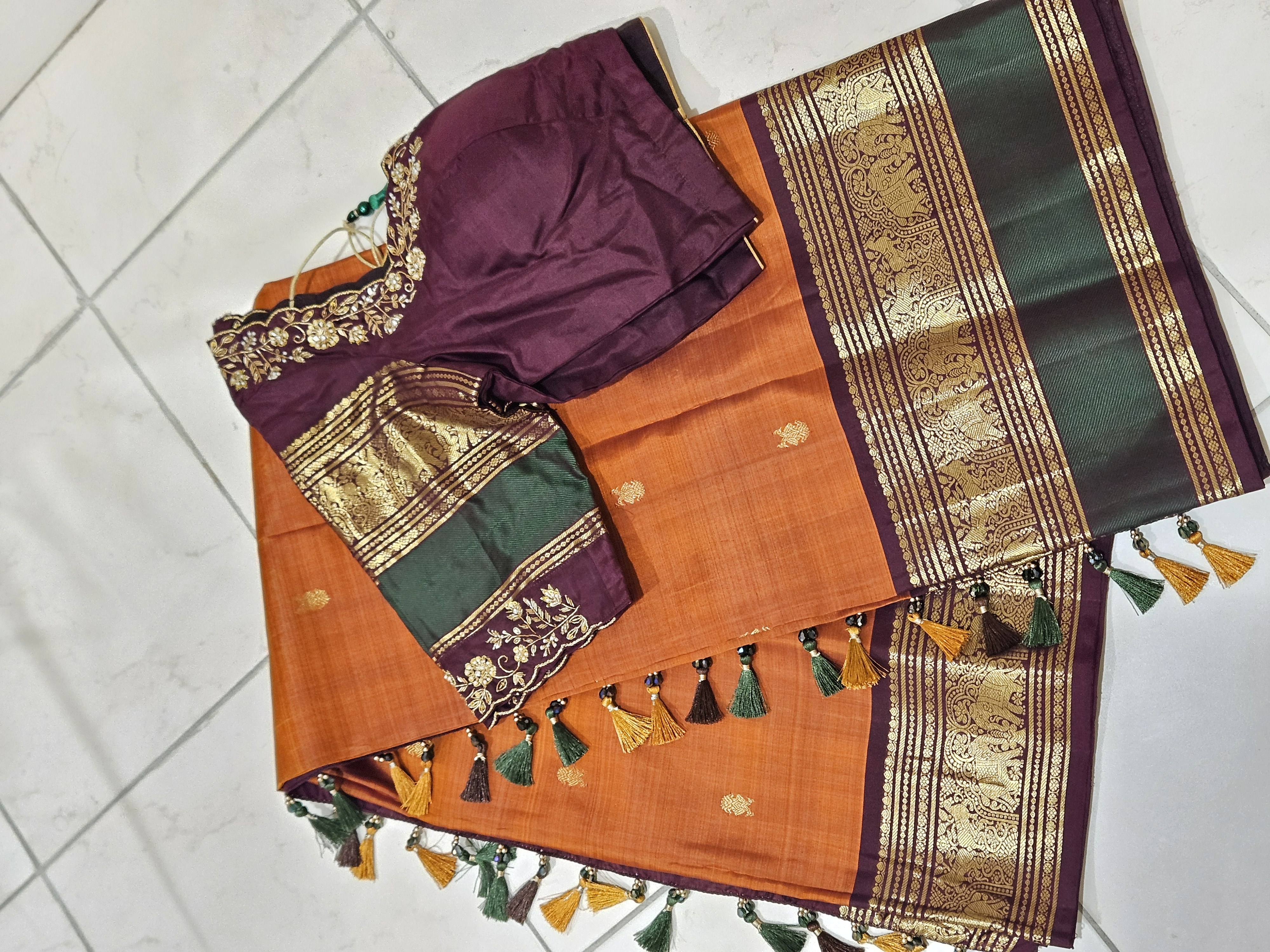 Rust orange and brown pure Kanchipuram silk saree with gold handwoven zari border, paired with a maroon embroidered blouse.