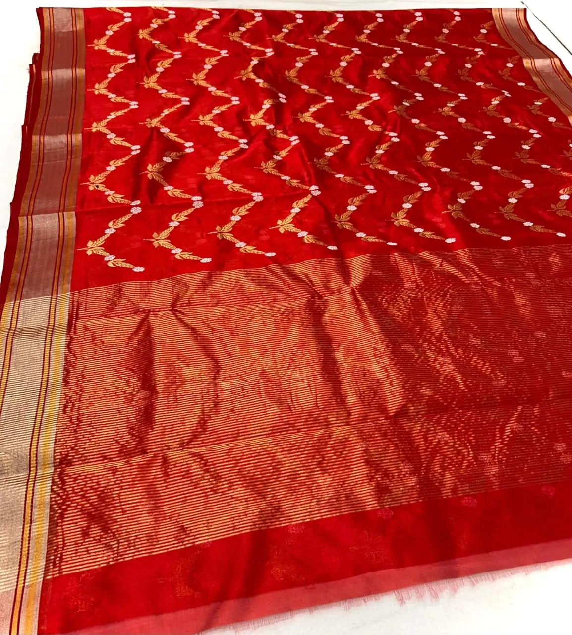 Handwoven Chanderi silk saree in rich red with intricate gold zari work, floral motifs, and elegant striped border