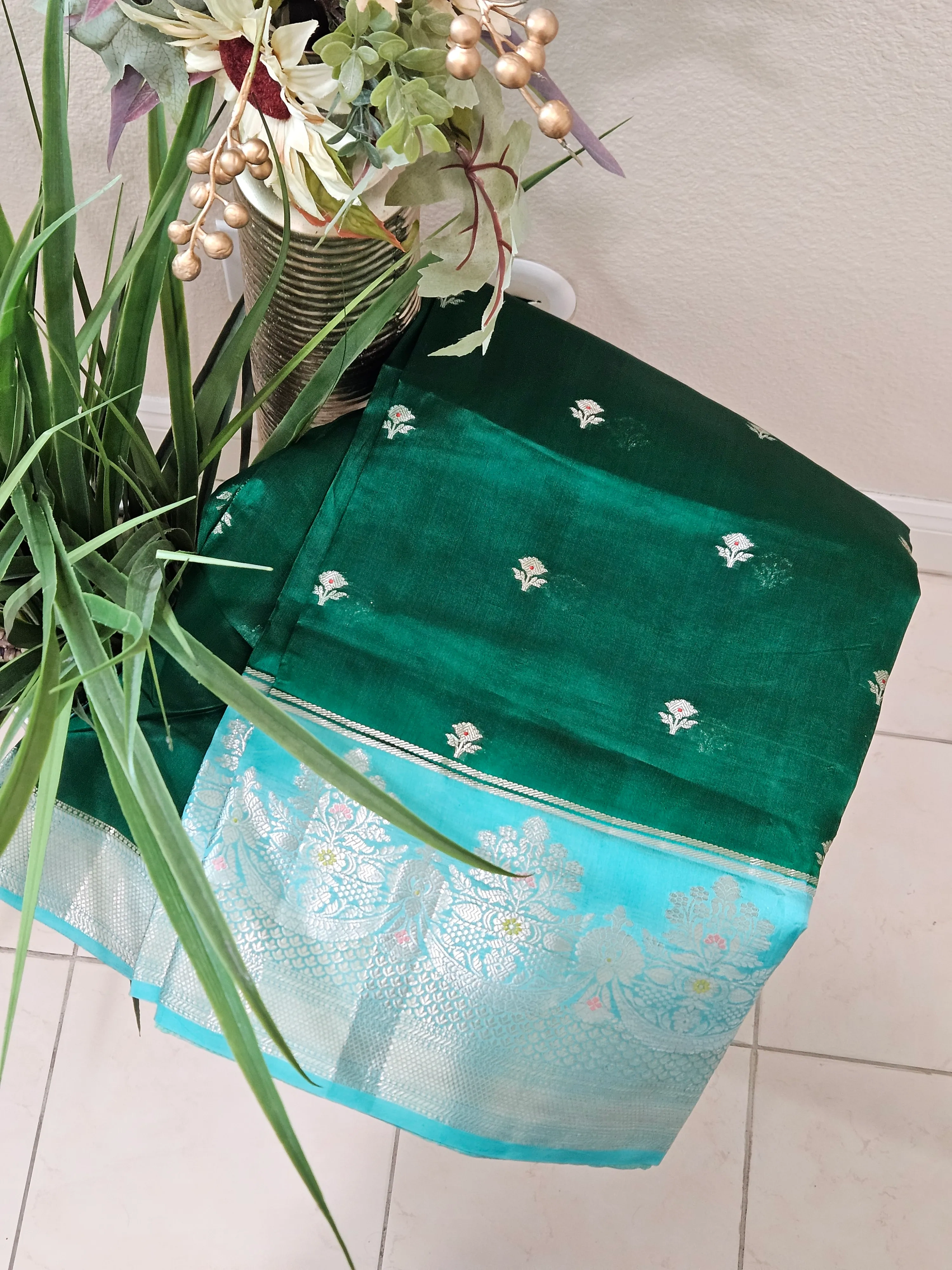 Handwoven pure raw mango silk saree in earthy yellow-green with silver zari border and small floral motifs displayed folded.
