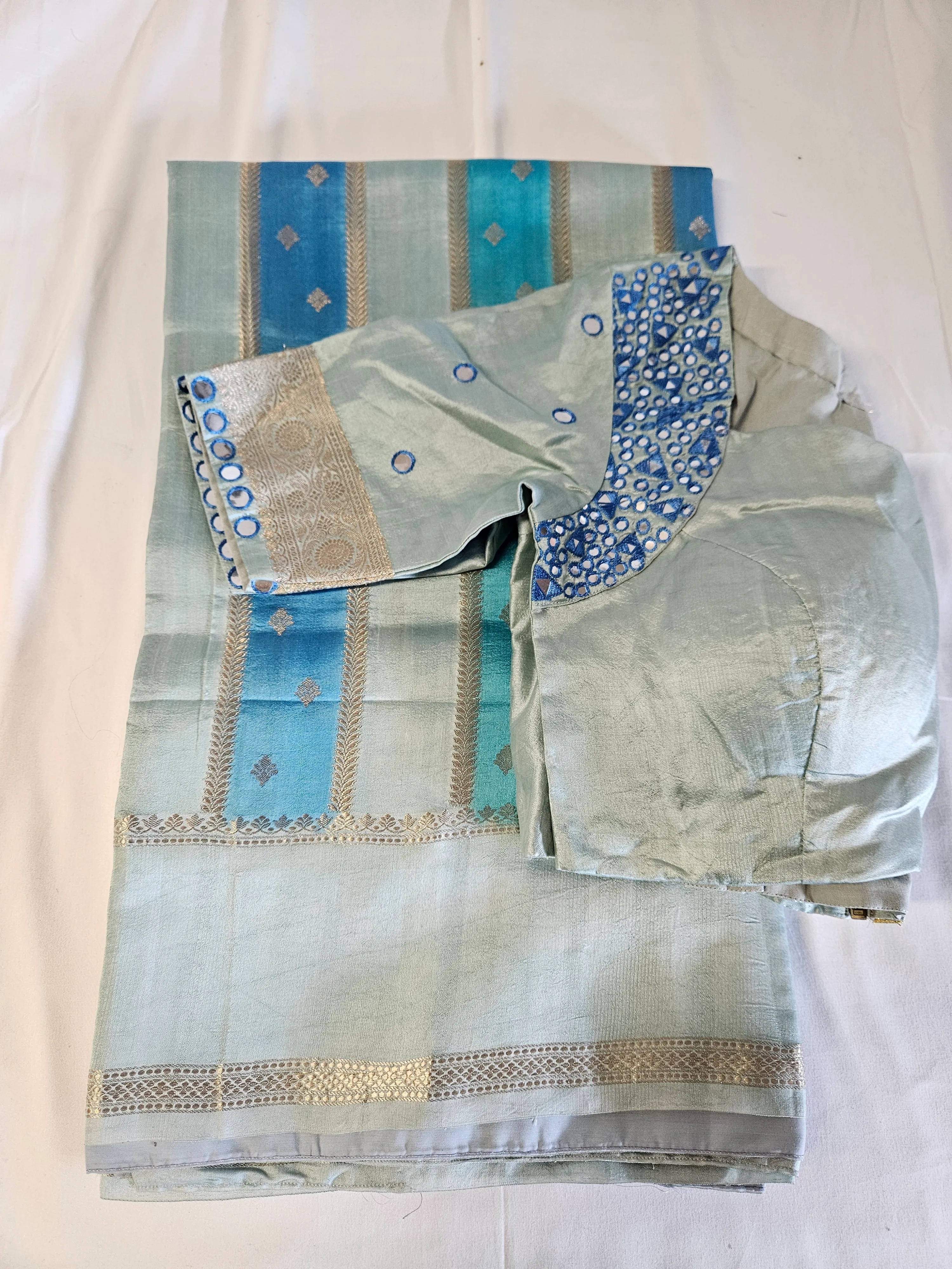 Handwoven light blue silk saree with silver zari borders, paired with a matching blouse featuring blue embroidery details.