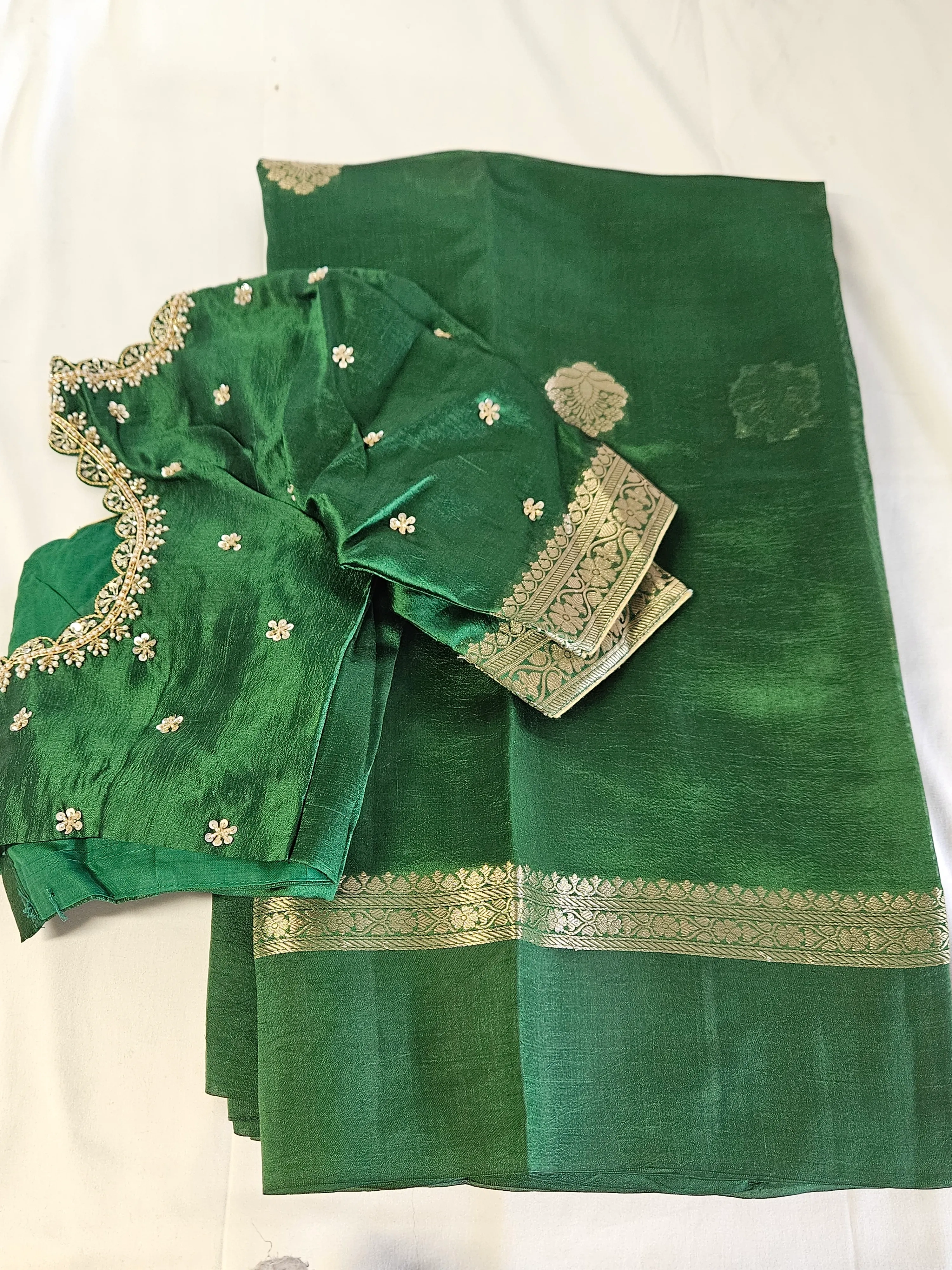Pure raw mango silk saree in rich green with gold zari border, paired with matching embroidered blouse, ideal for weddings.