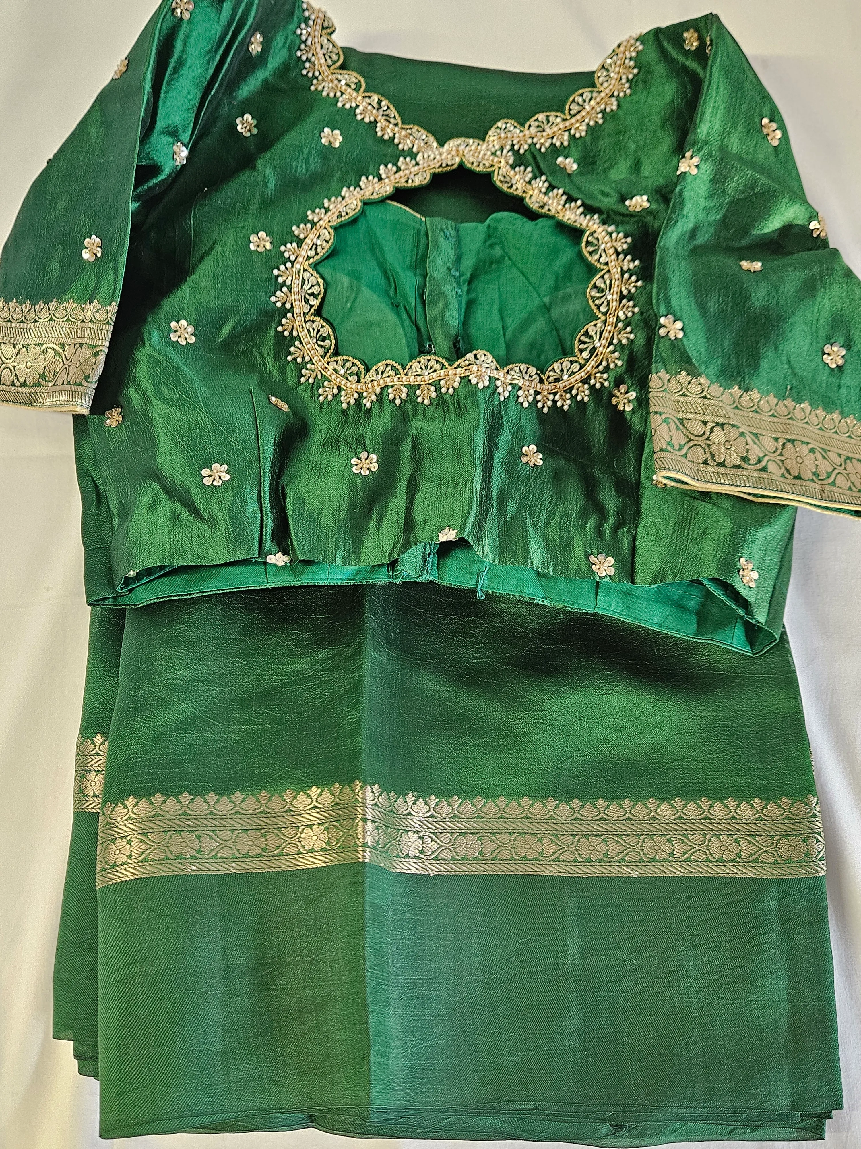Pure raw mango silk saree in rich emerald green with gold zari border, paired with matching embroidered blouse for festive wear