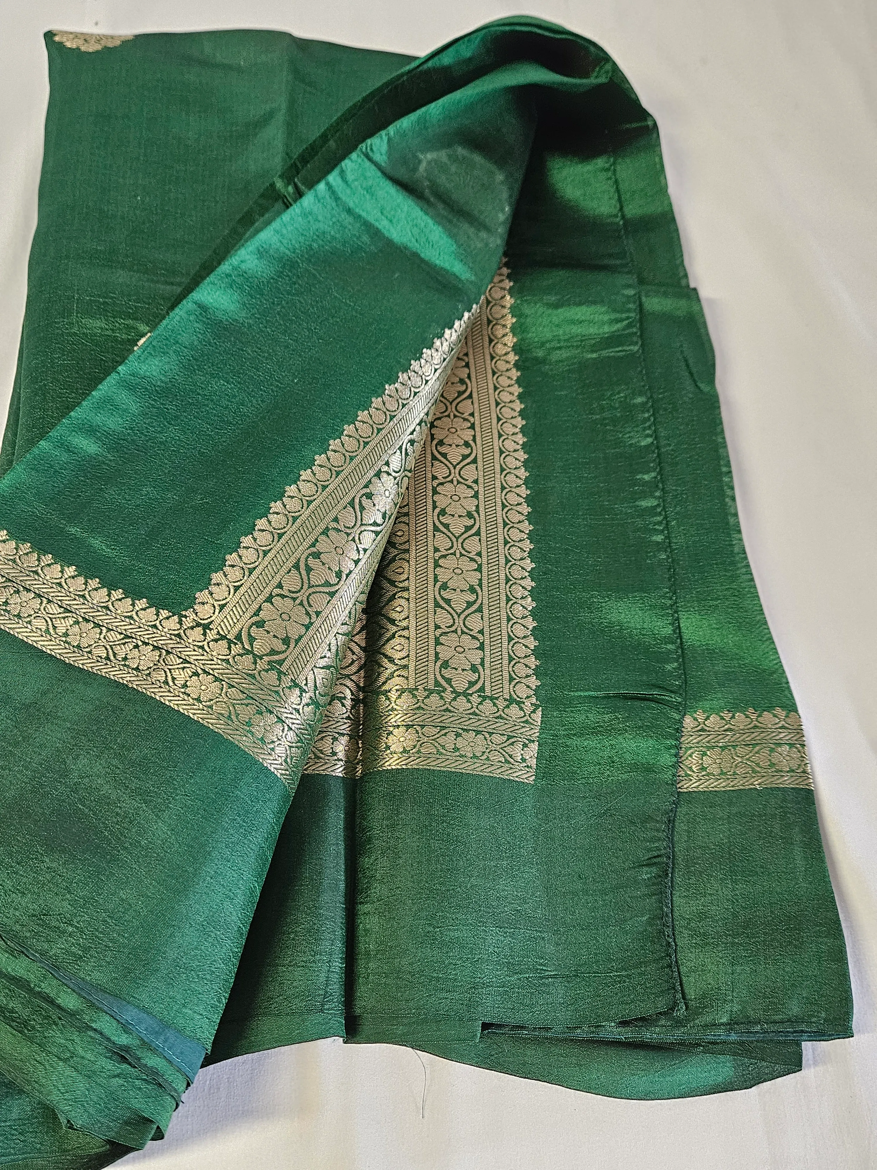 Pure raw mango silk saree in rich emerald green with intricate gold zari border, perfect for weddings and festive occasions