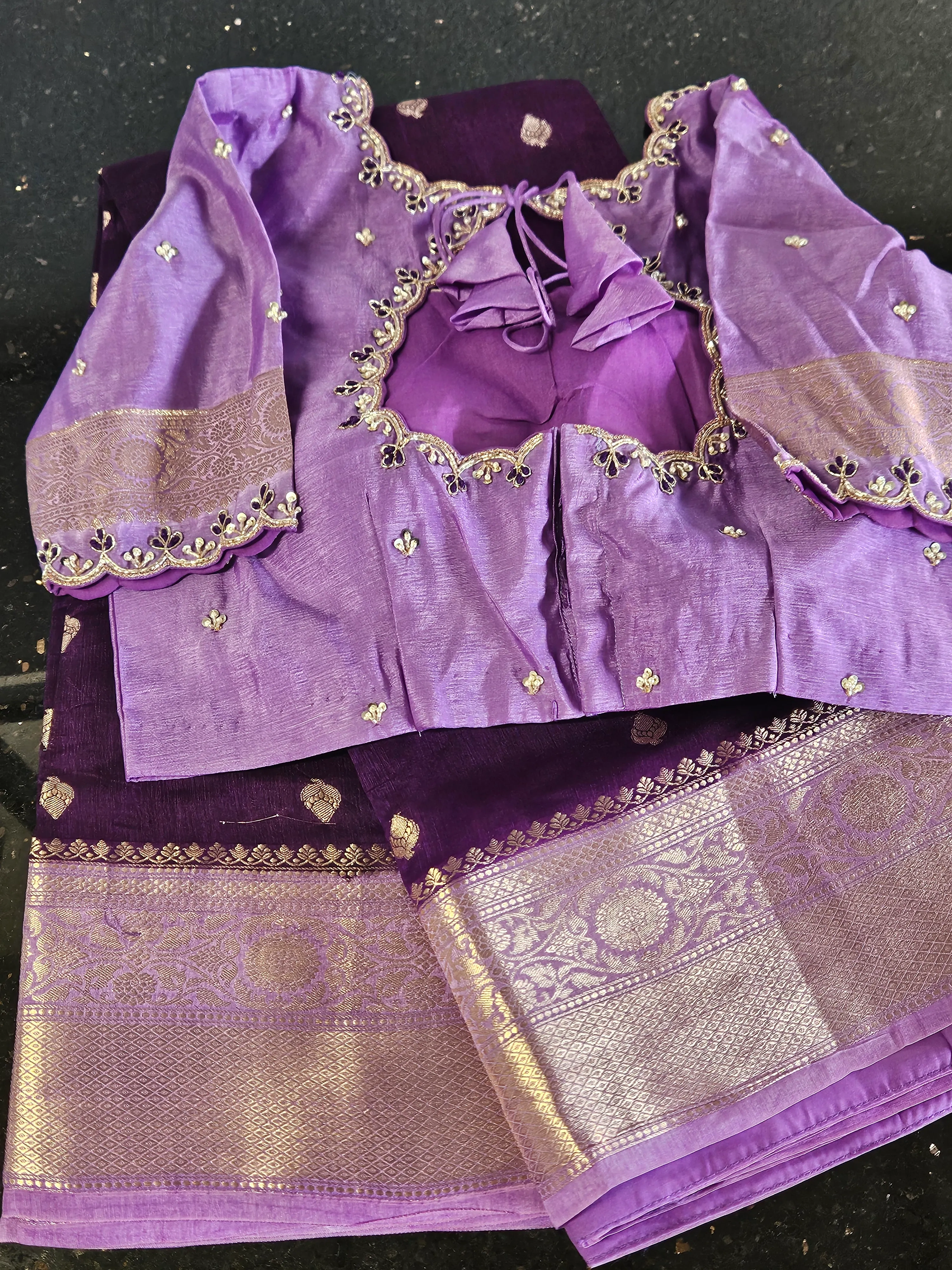 Purple and gold handwoven silk saree with intricate zari border, paired with a matching embroidered blouse for festive wear.