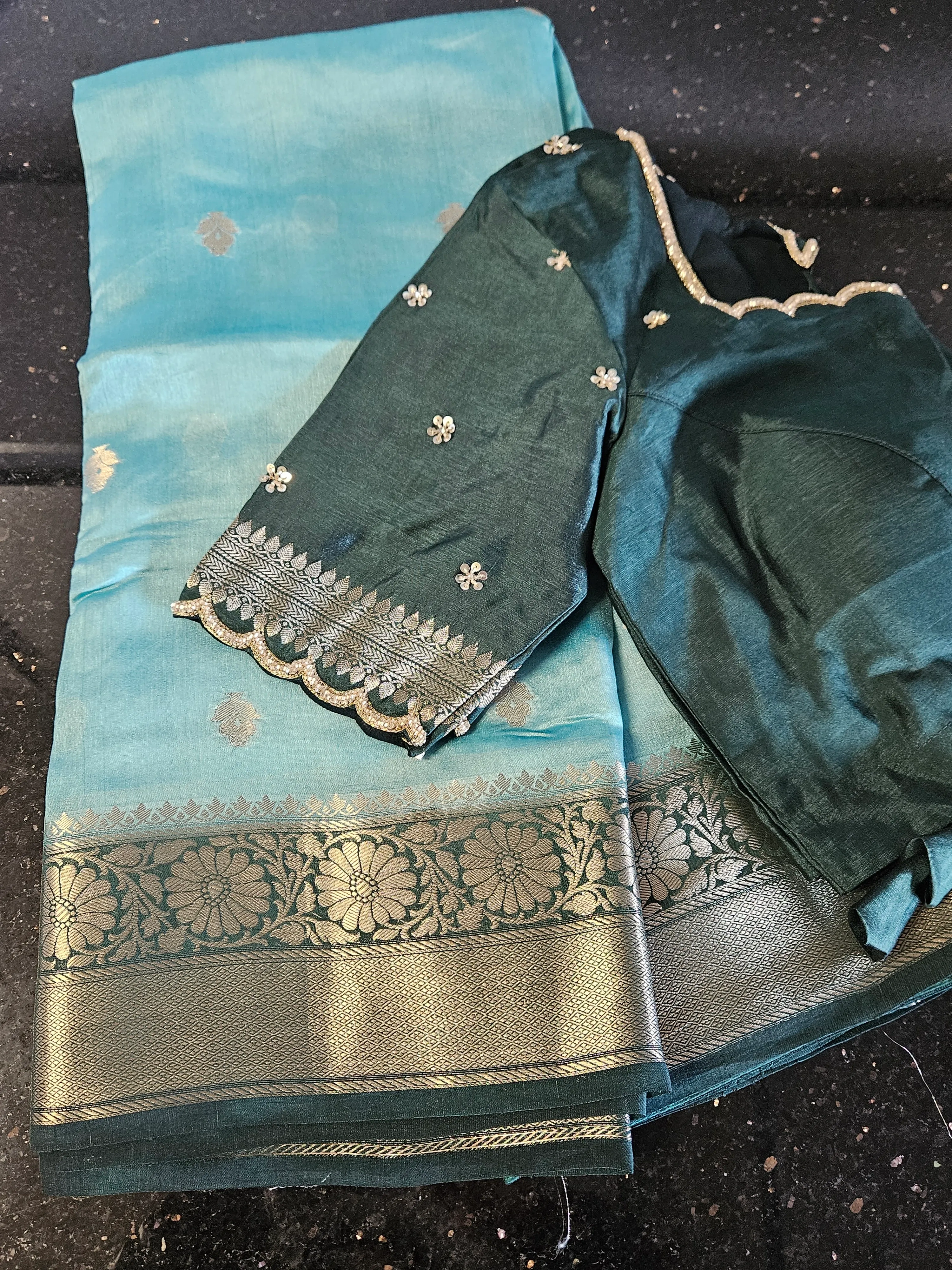 Luxury pure raw mango silk saree in teal blue with silver zari floral motifs and border, paired with matching blouse piece
