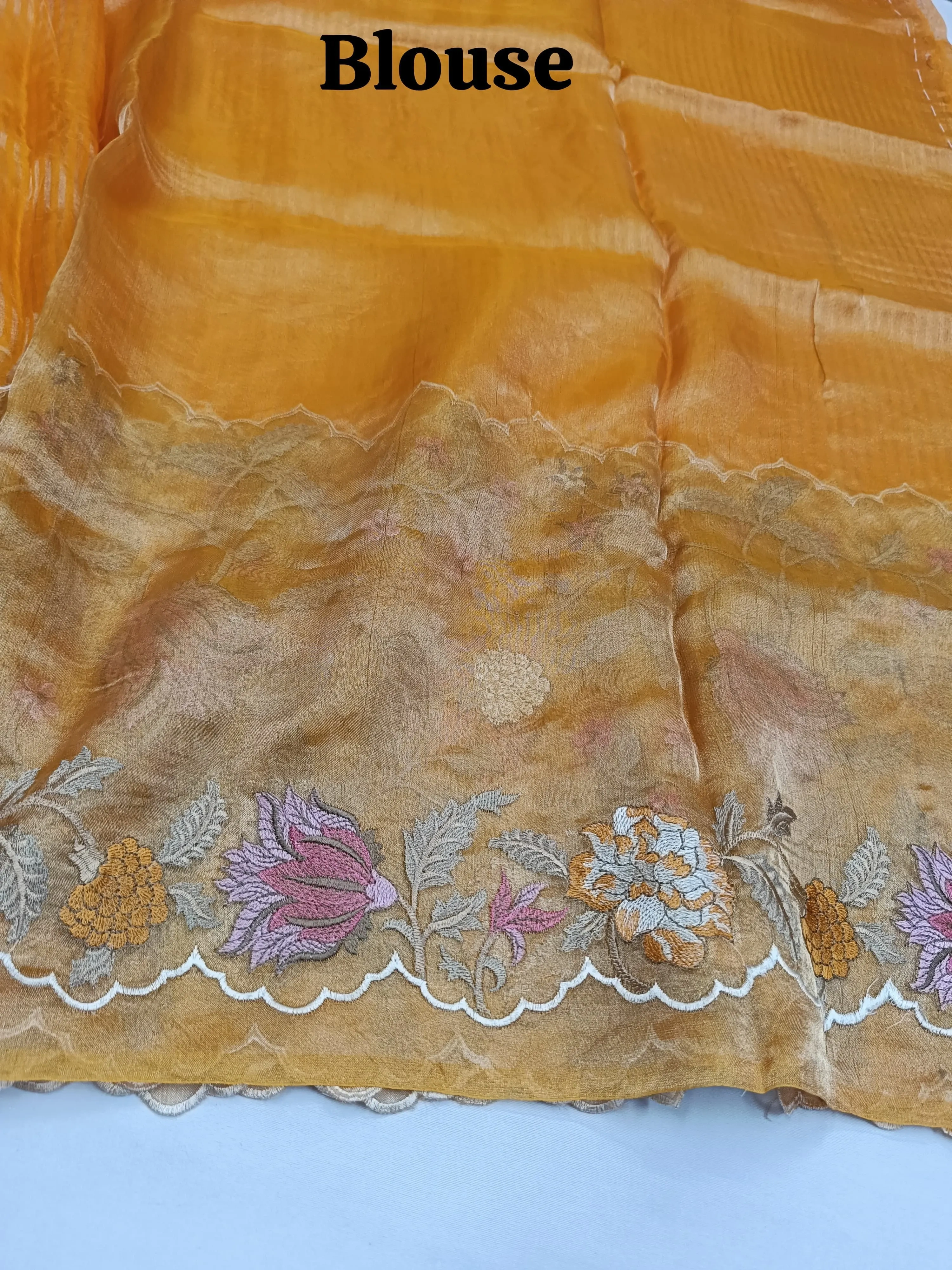 Pure Banarasi Kora tissue saree in golden yellow with intricate gold zari and multicolor floral embroidery on the border.