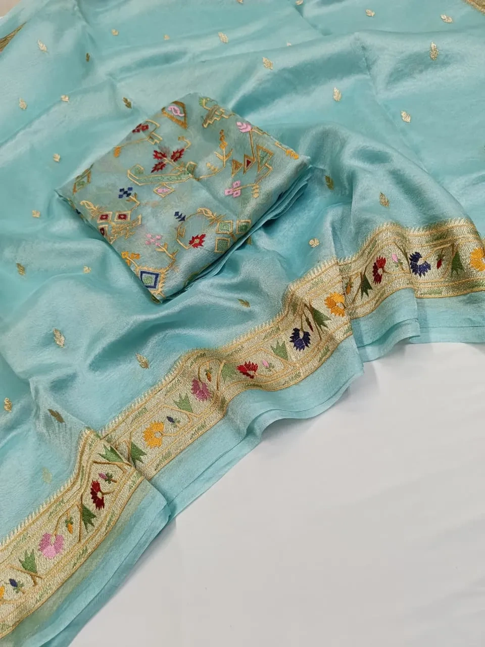 Pure Banarasi Kora tissue saree in pastel blue with handwoven golden zari border and multicolor floral motifs, ideal for weddings.