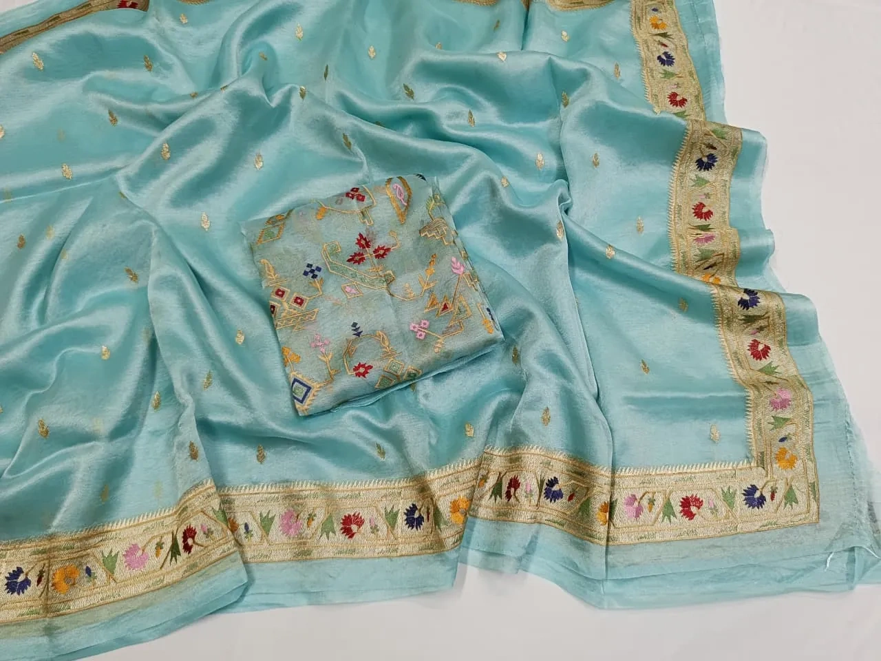 Pure Banarasi Kora tissue saree in pastel blue with handwoven golden zari and multicolor floral border, ideal for weddings