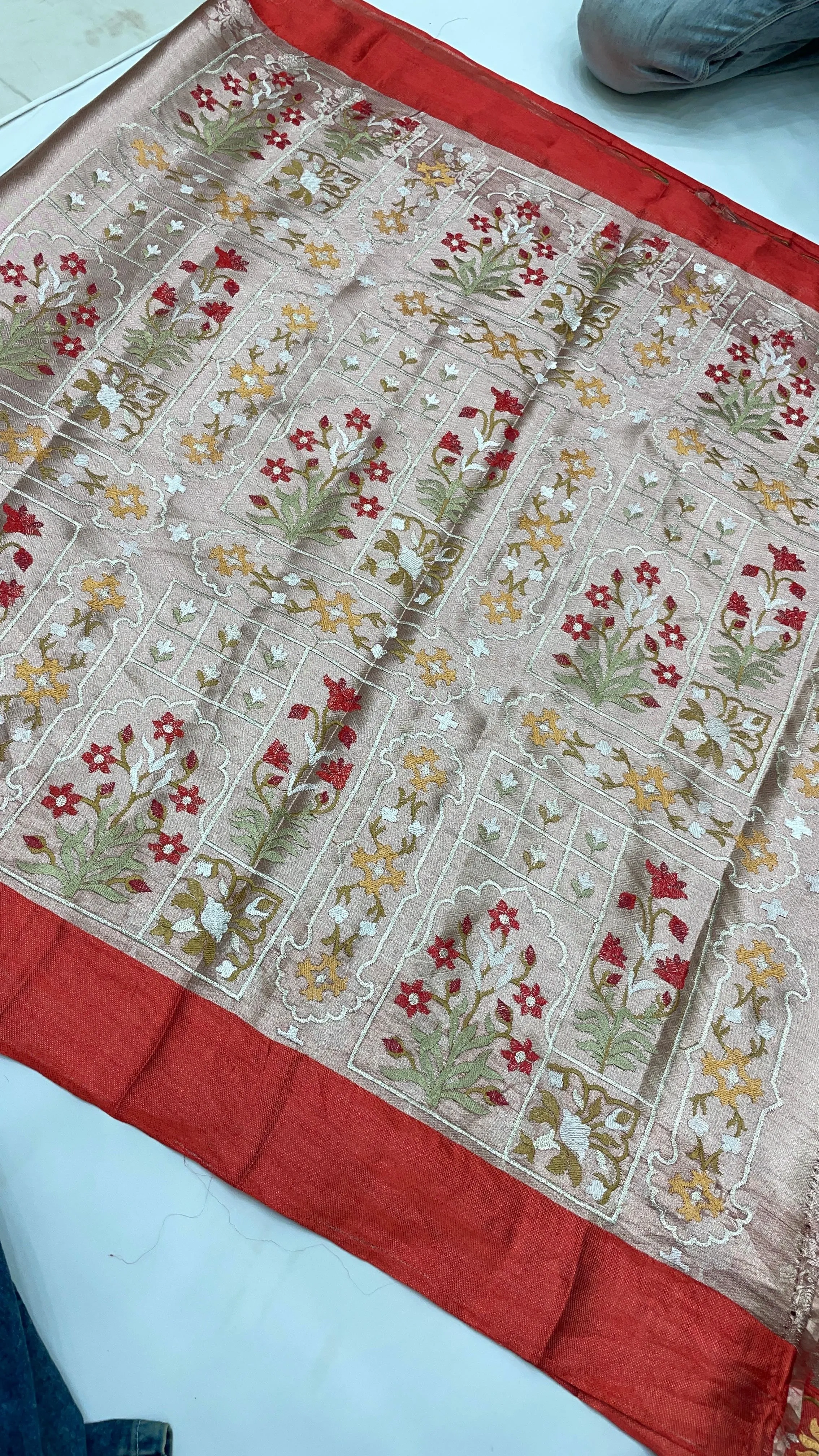 Handwoven golden Banarasi tissue saree with intricate floral brocade patterns in red, green, and gold, red border