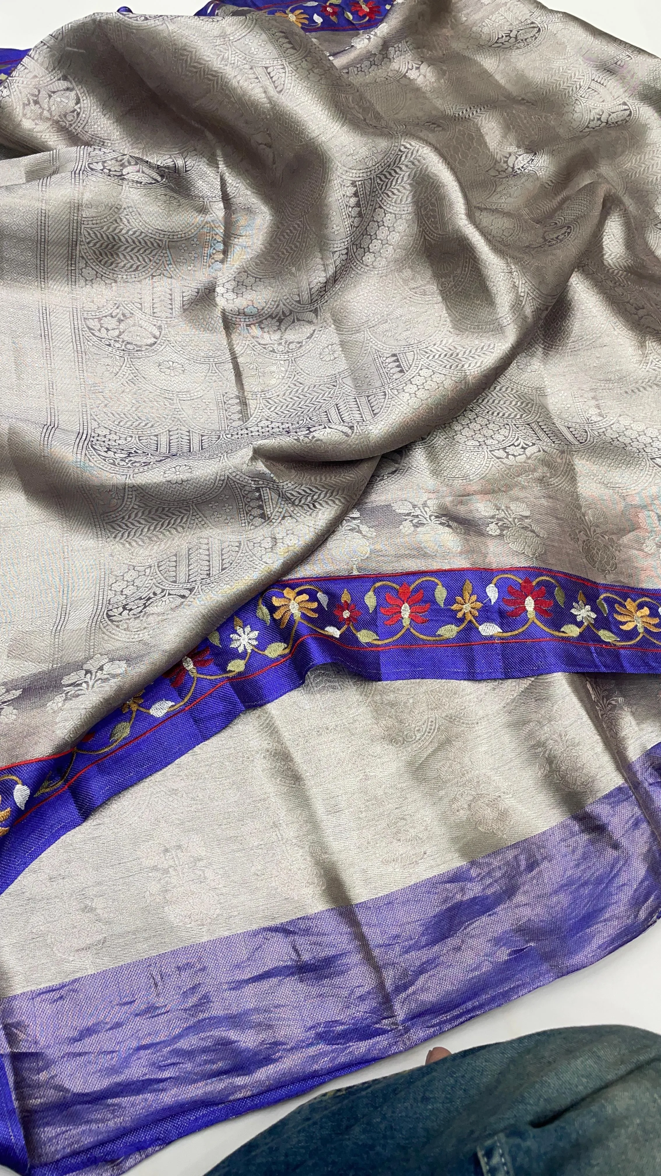 Pure Banarasi gold tissue brocade saree with intricate silver zari work and a rich blue border featuring floral motifs.