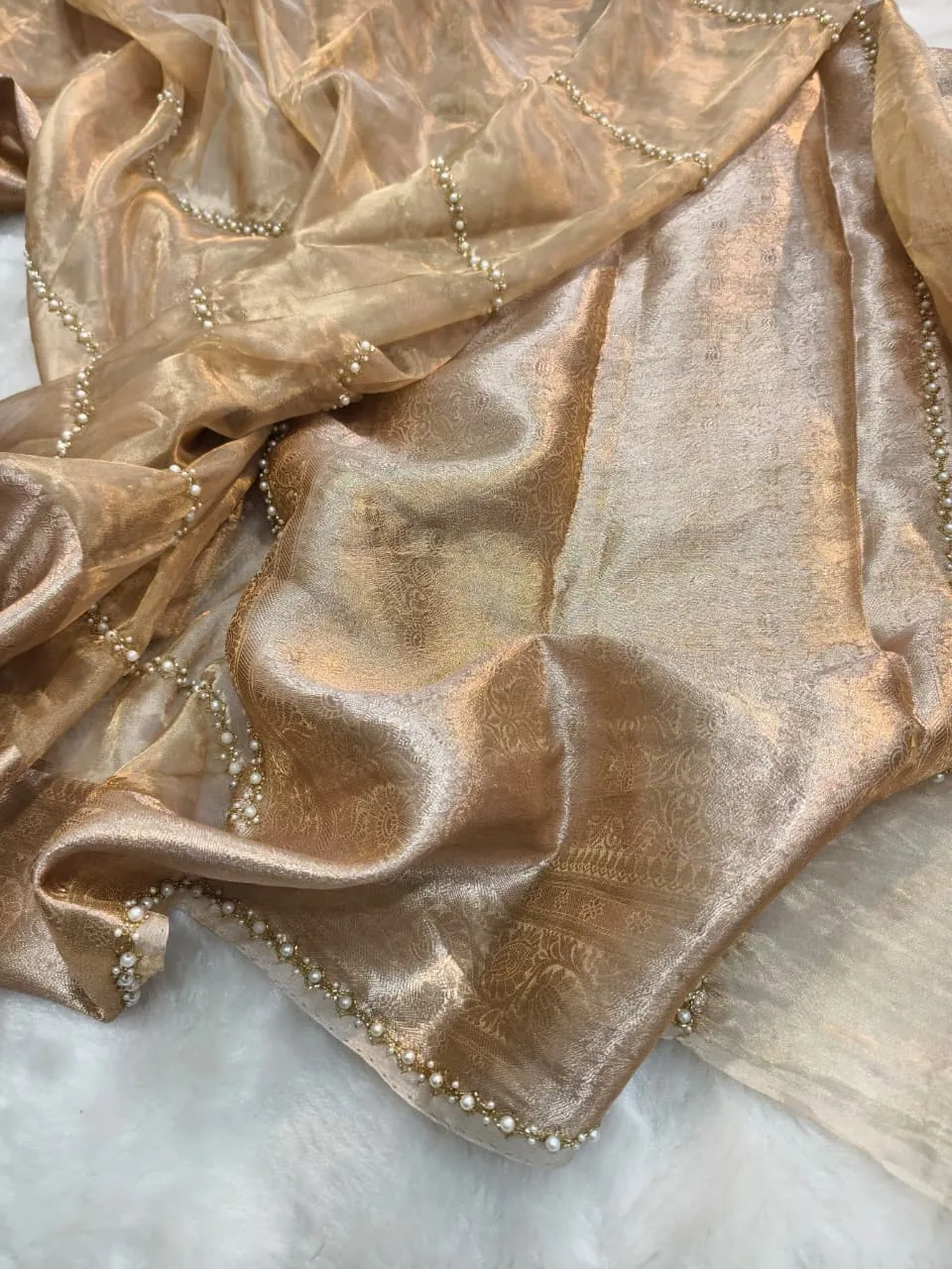 Handwoven Banarasi Kora tissue saree in gold with intricate zari work and pearl bead edging, perfect for weddings.