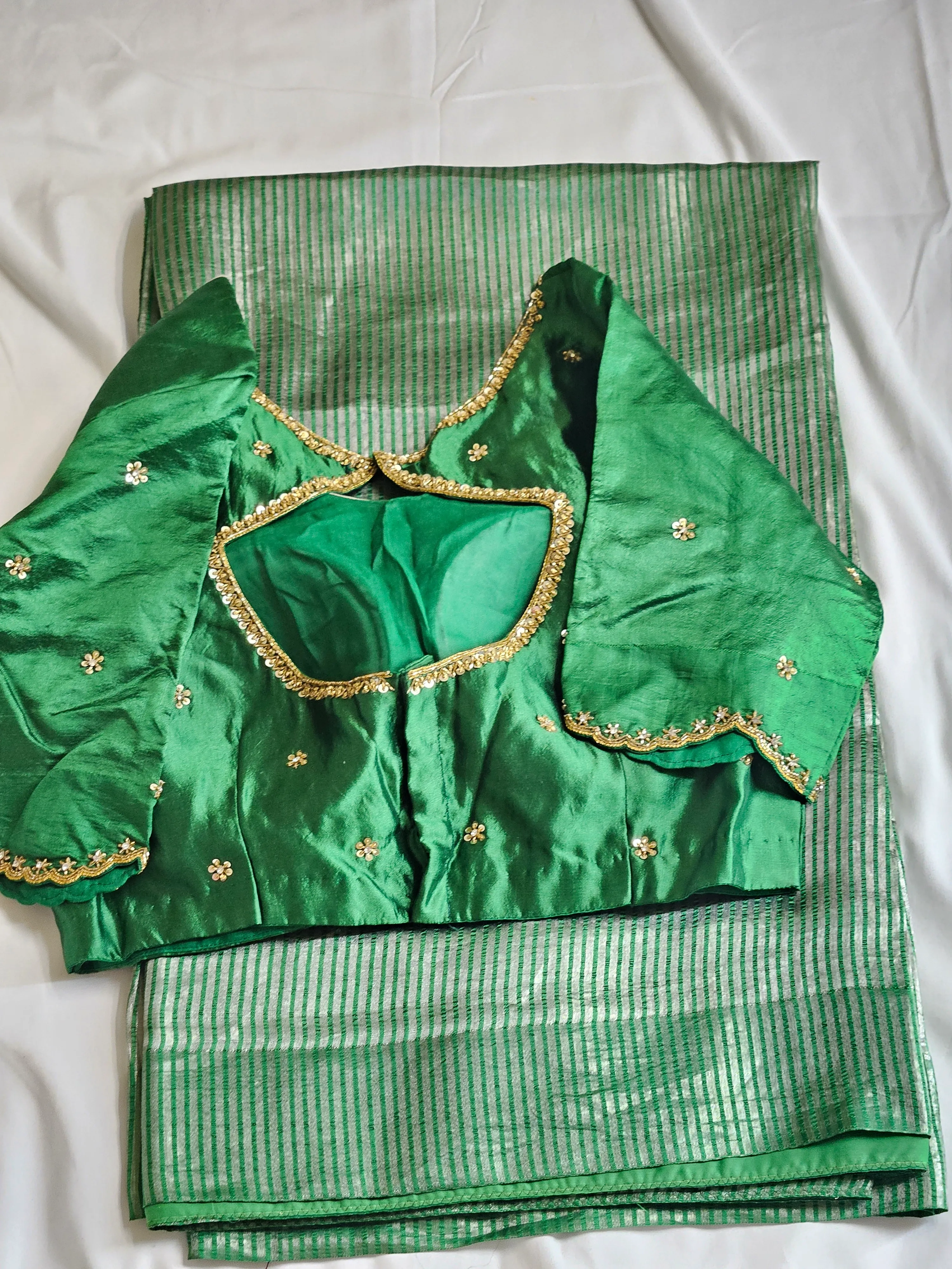 Handwoven Banarasi tissue saree in green with gold-silver zari stripes, paired with an embellished green blouse.
