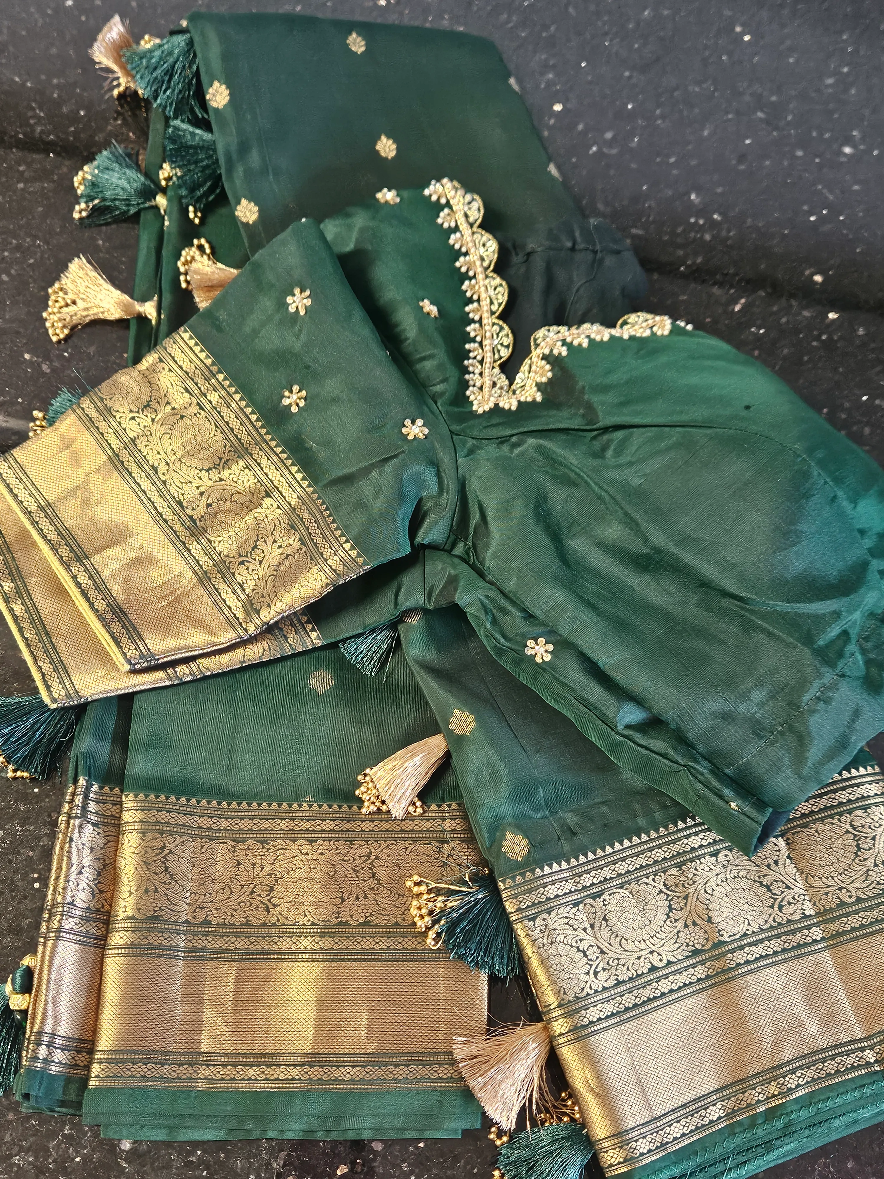 Handwoven Kanchipuram silk saree in deep green with intricate gold zari borders, small motifs, and tassel accents, ideal for weddings.