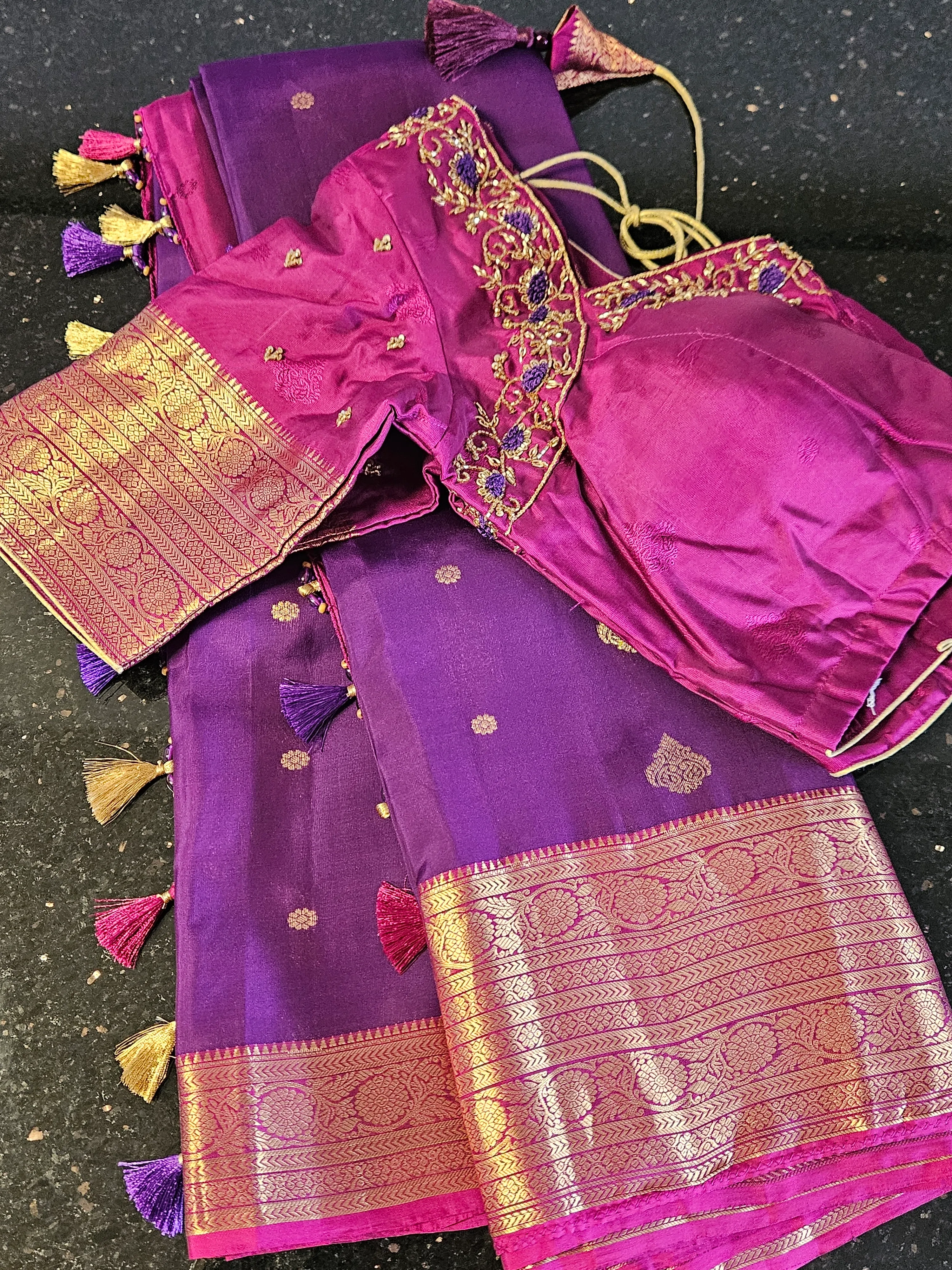 Handcrafted pure Kanchipuram silk saree in rich purple with gold zari border, paired with a magenta embroidered blouse.