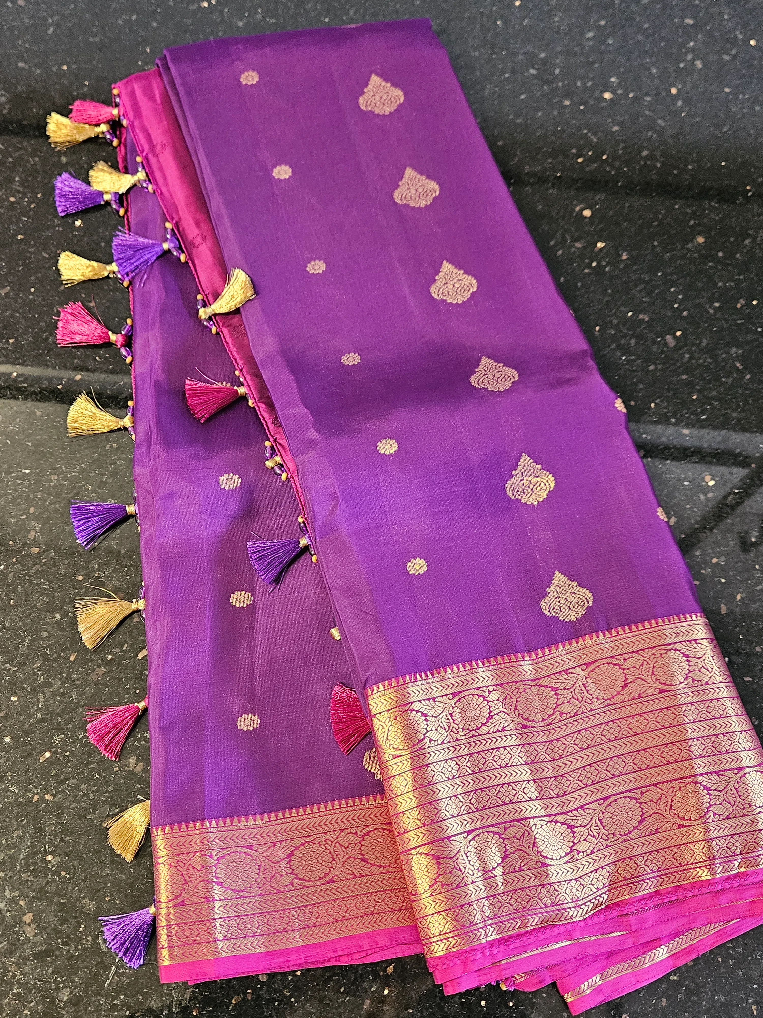 Handcrafted pure Kanchipuram silk saree in vibrant purple with gold zari motifs, ornate border, and colorful tassels