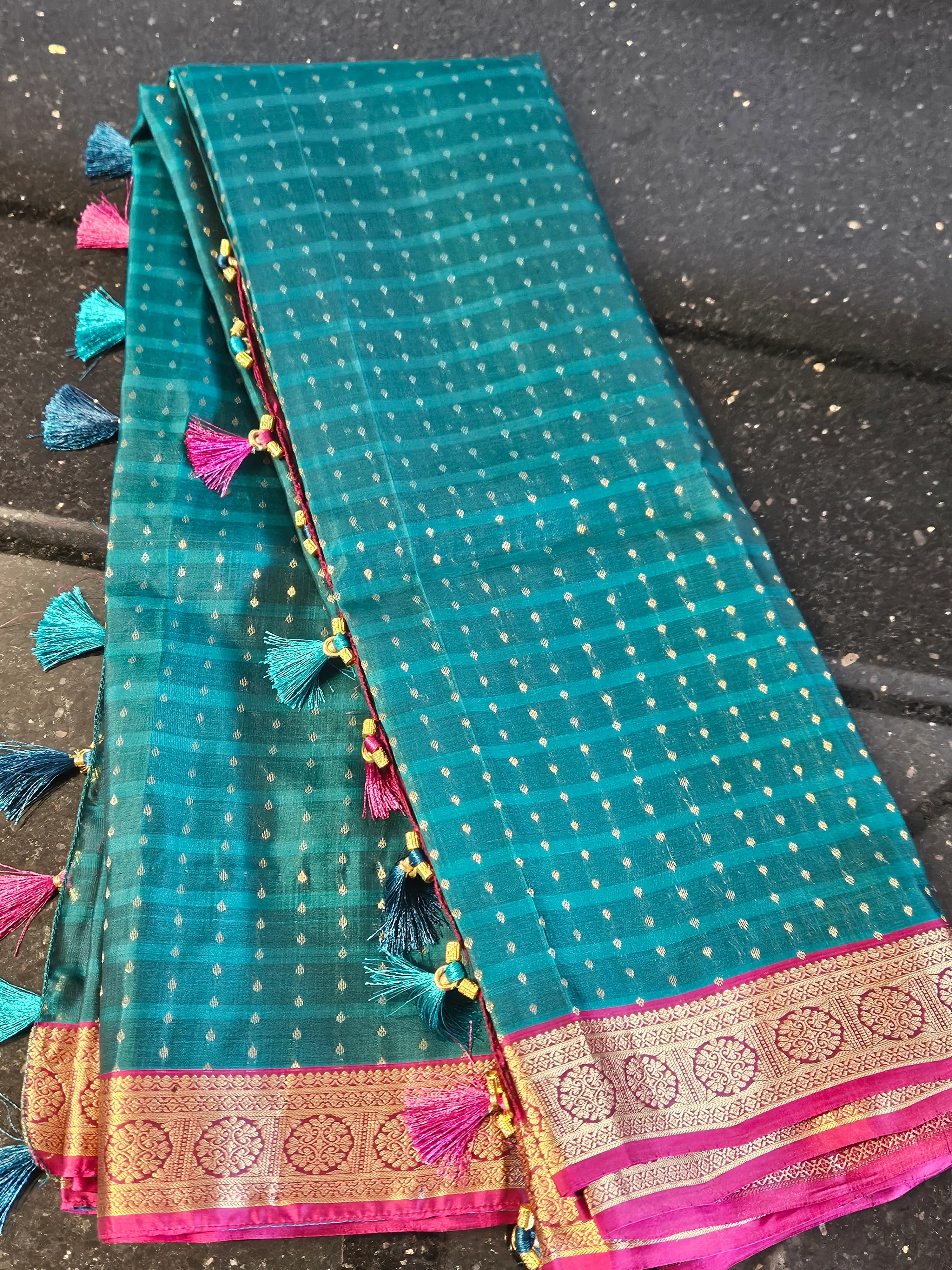 Handwoven pure Kanchipuram silk wedding saree in teal with gold and silver zari work, pink border, and tassel accents