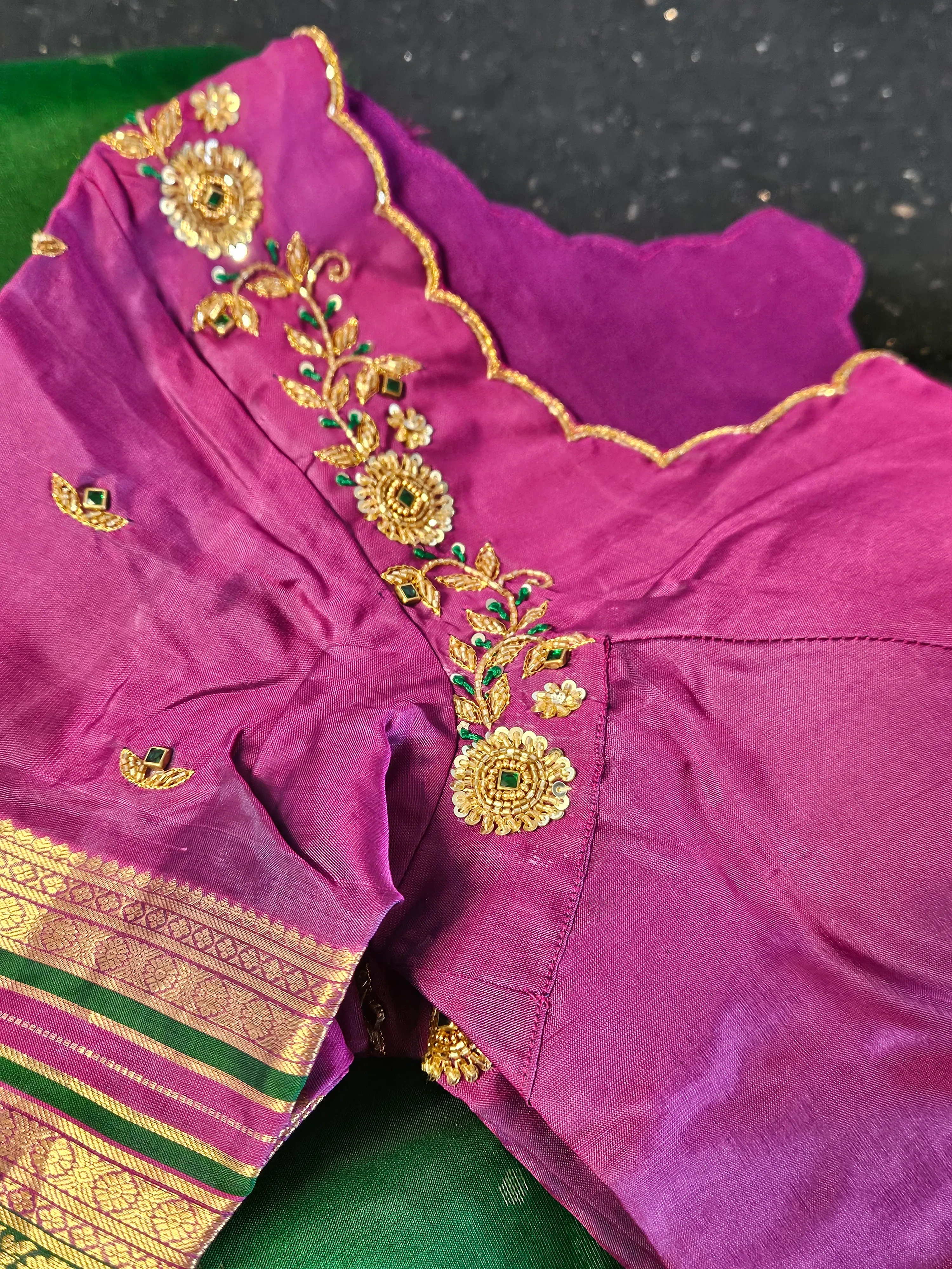 Pure Kanchipuram silk saree in rich purple with gold zari handwoven border, floral embroidery, and green accents.