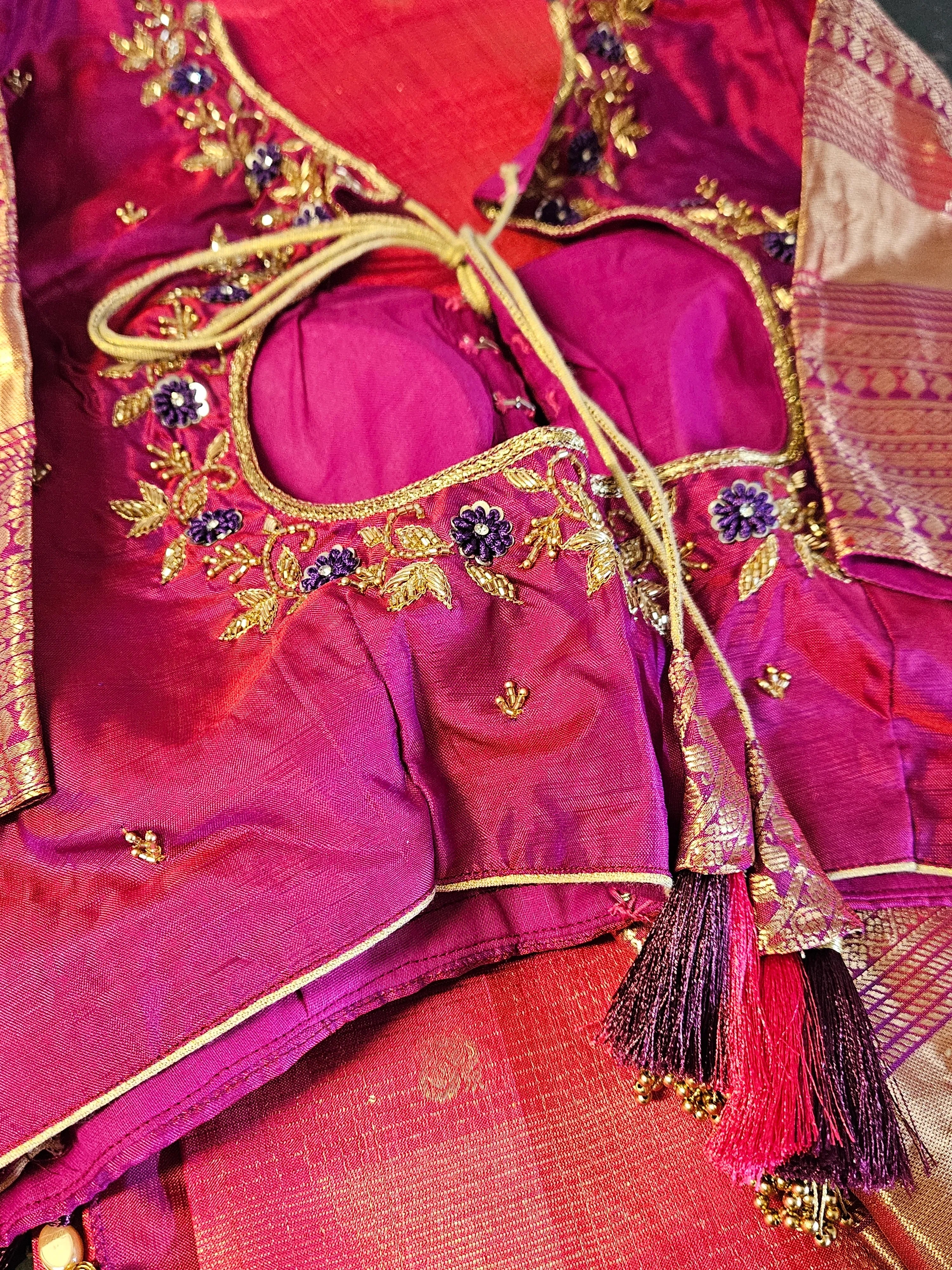 Handwoven pure Kanchipuram silk saree in rich magenta with gold and silver zari, floral embroidery, and tassel accents.