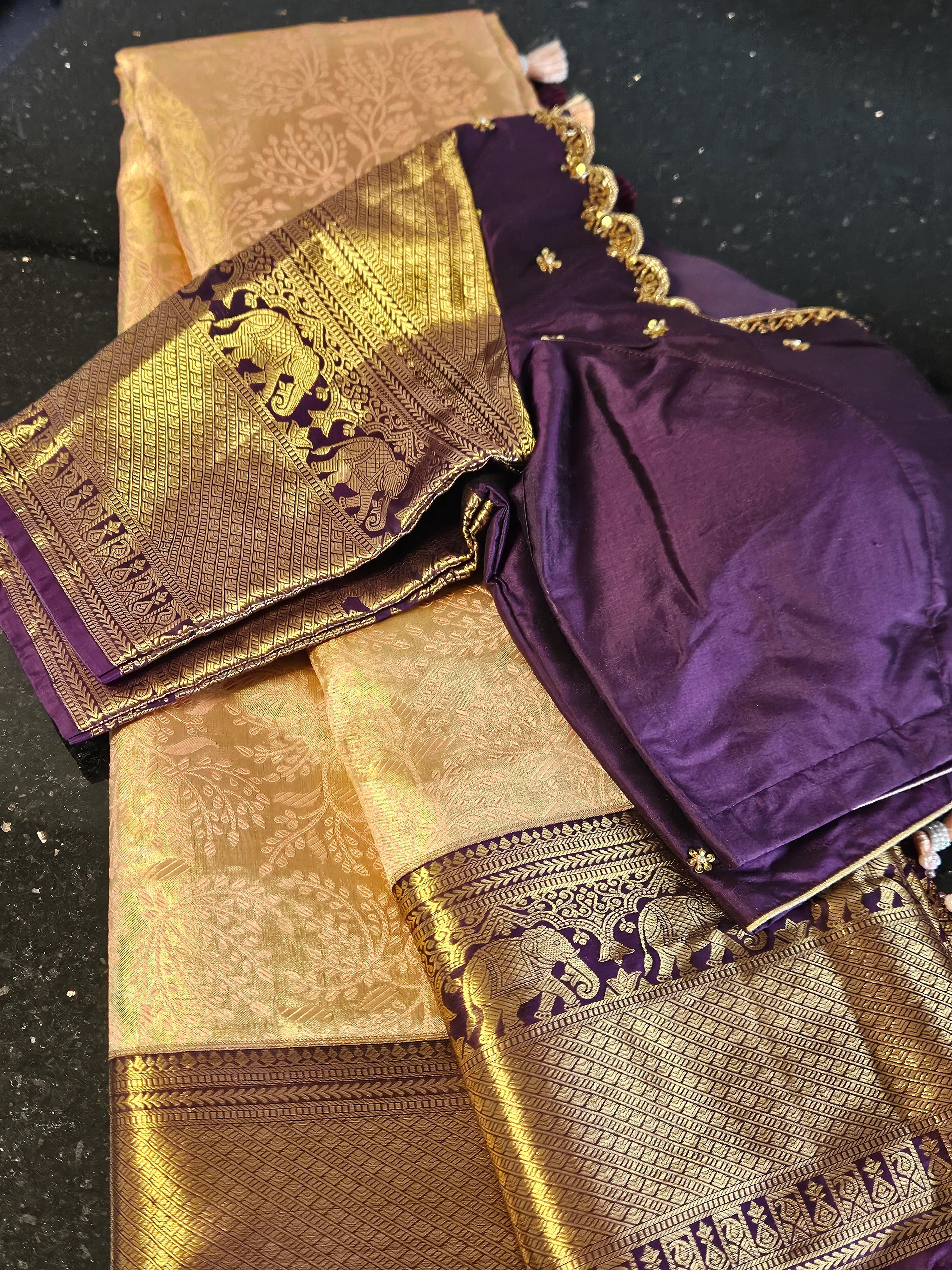 Pure Kanchipuram silk wedding saree in gold with intricate handwoven gold and silver zari motifs, paired with a rich purple blouse.