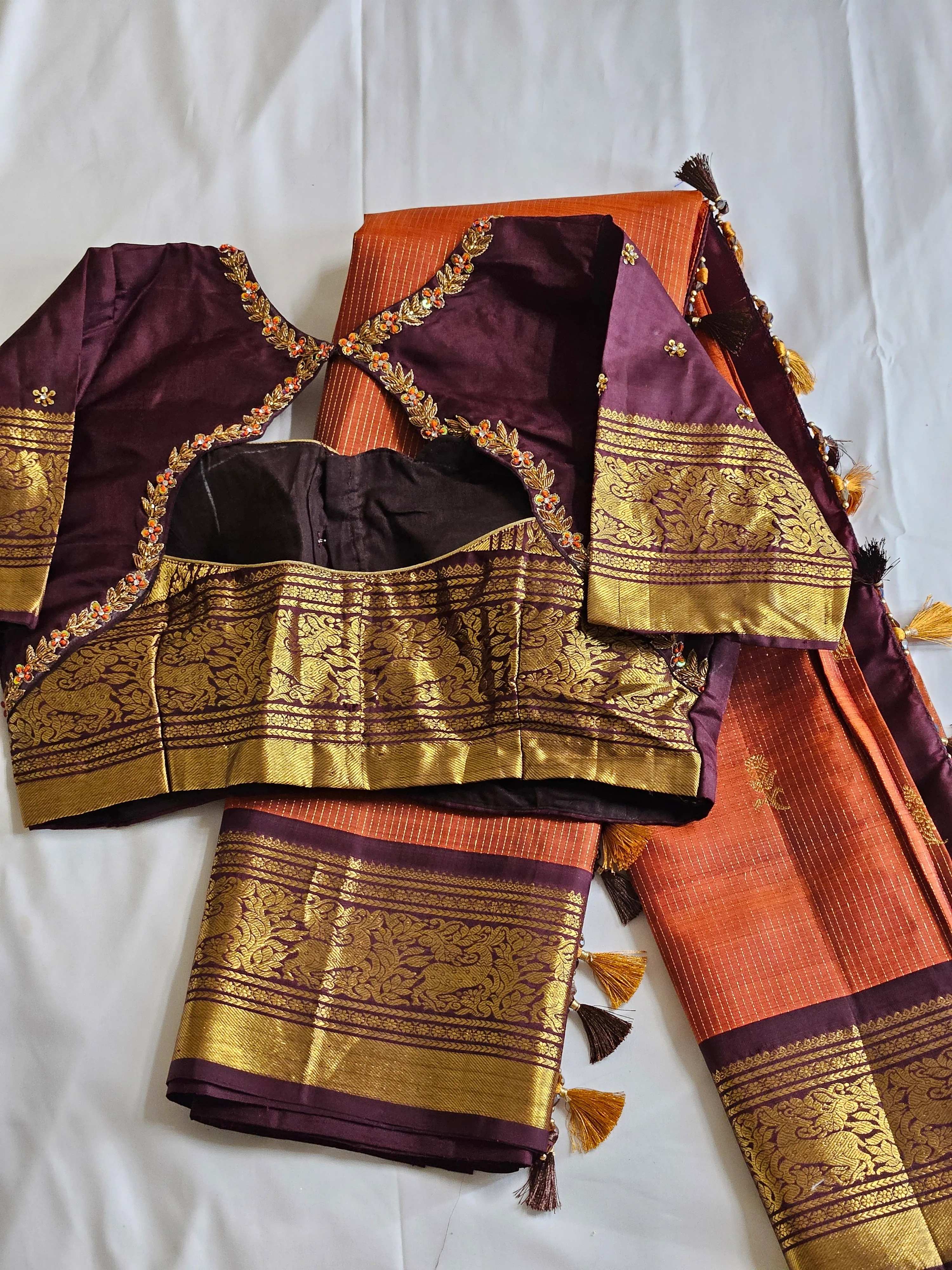 Handwoven pure Kanchipuram silk saree in golden yellow with rich gold zari work, paired with a purple blouse featuring intricate embroidery.