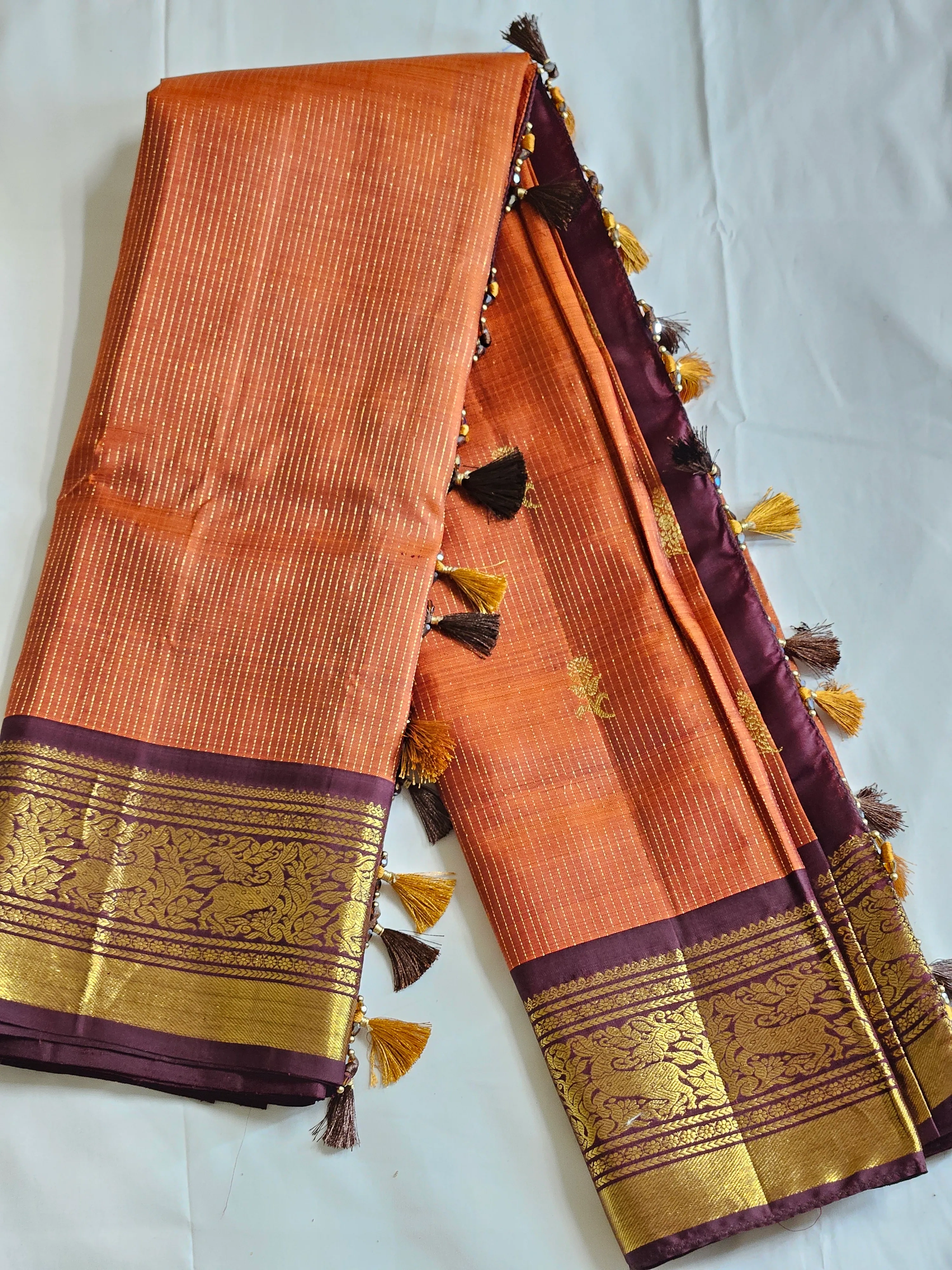 Handwoven pure Kanchipuram silk saree in golden yellow with intricate gold zari work and rich purple borders with tassels