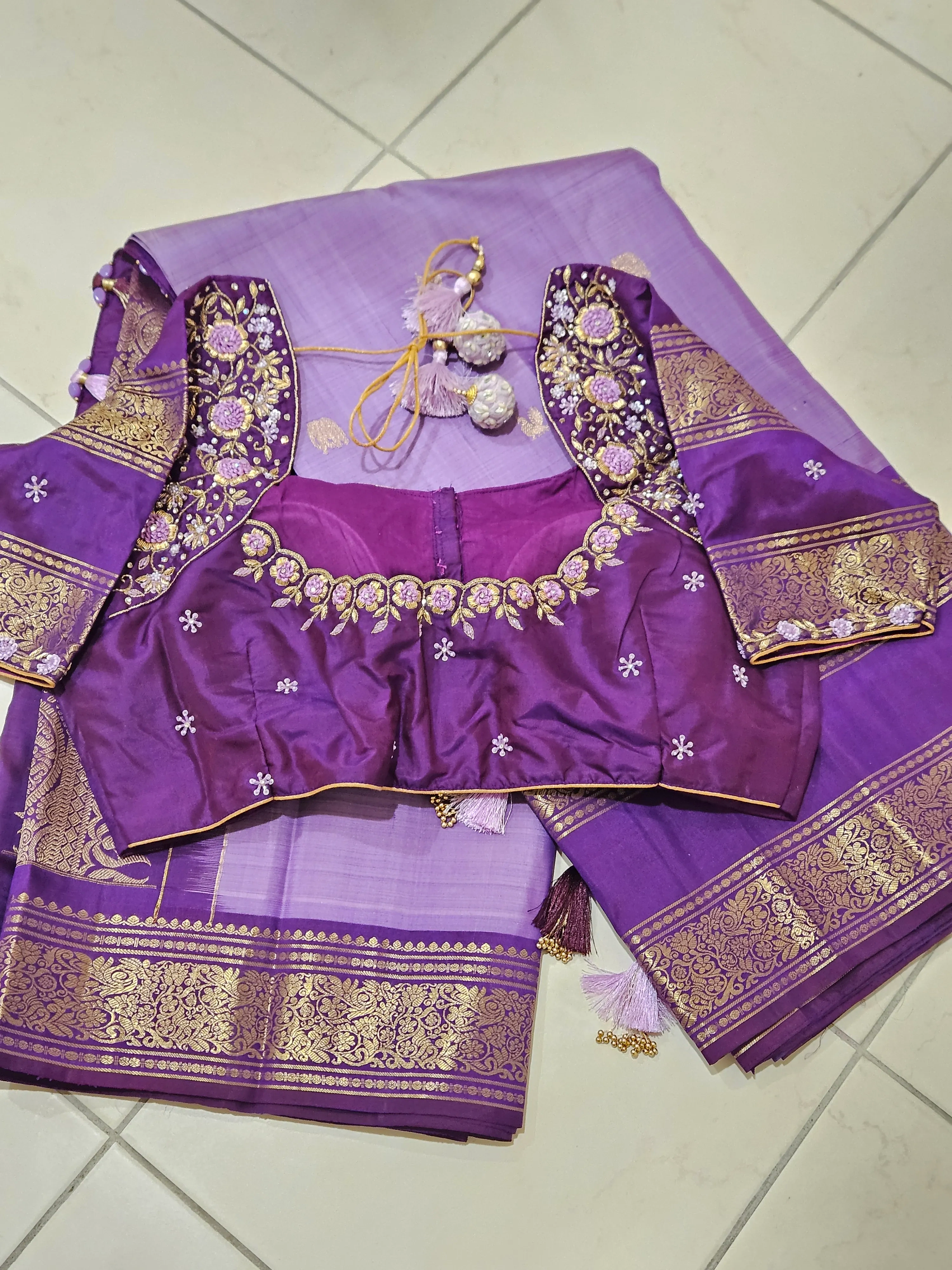 Pure Kanchipuram silk saree in rich purple with gold and silver zari borders, paired with an embellished blouse.