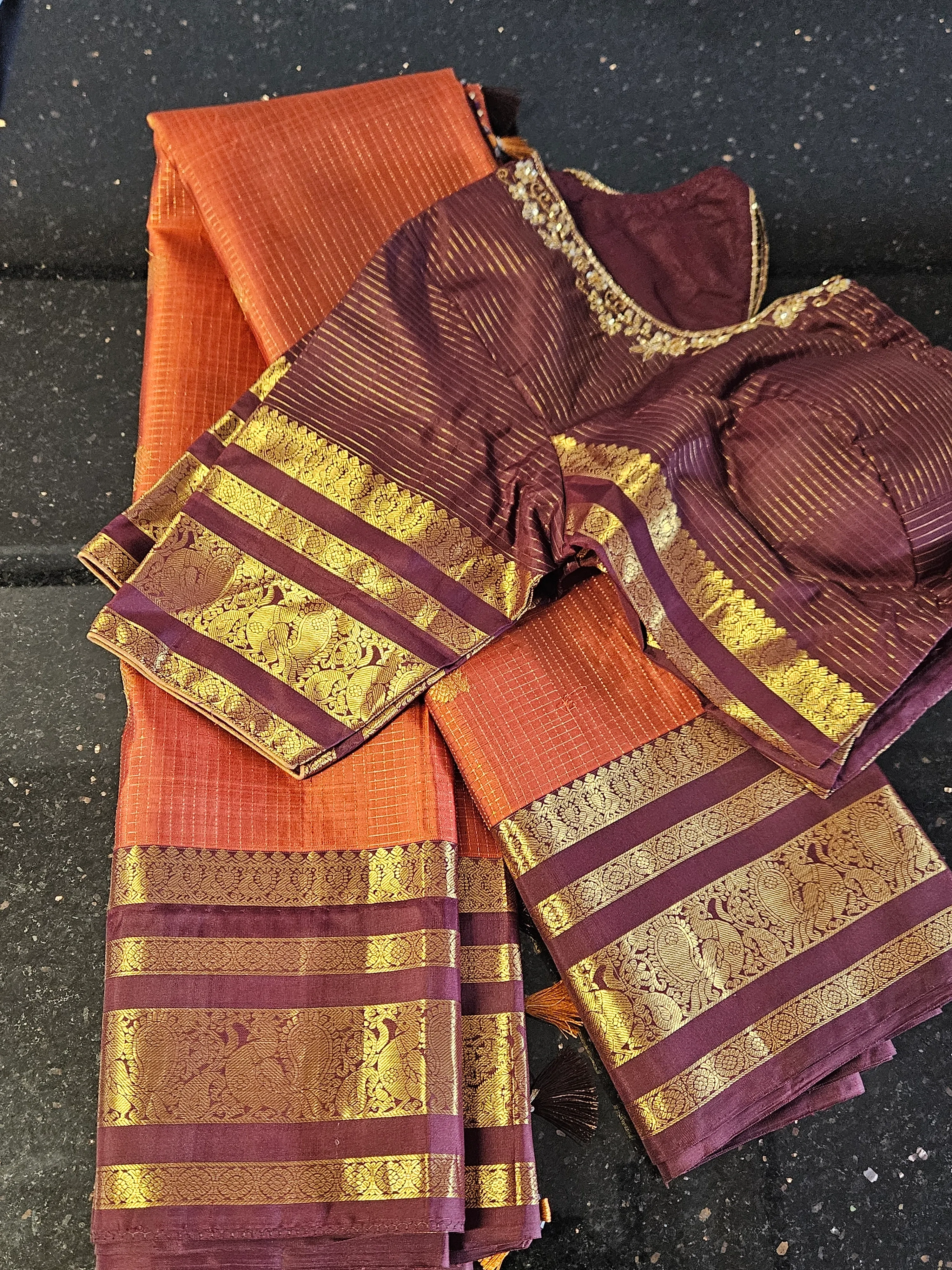 Handwoven Kanchipuram silk saree in rich orange and maroon with intricate gold zari borders, paired with matching blouse.