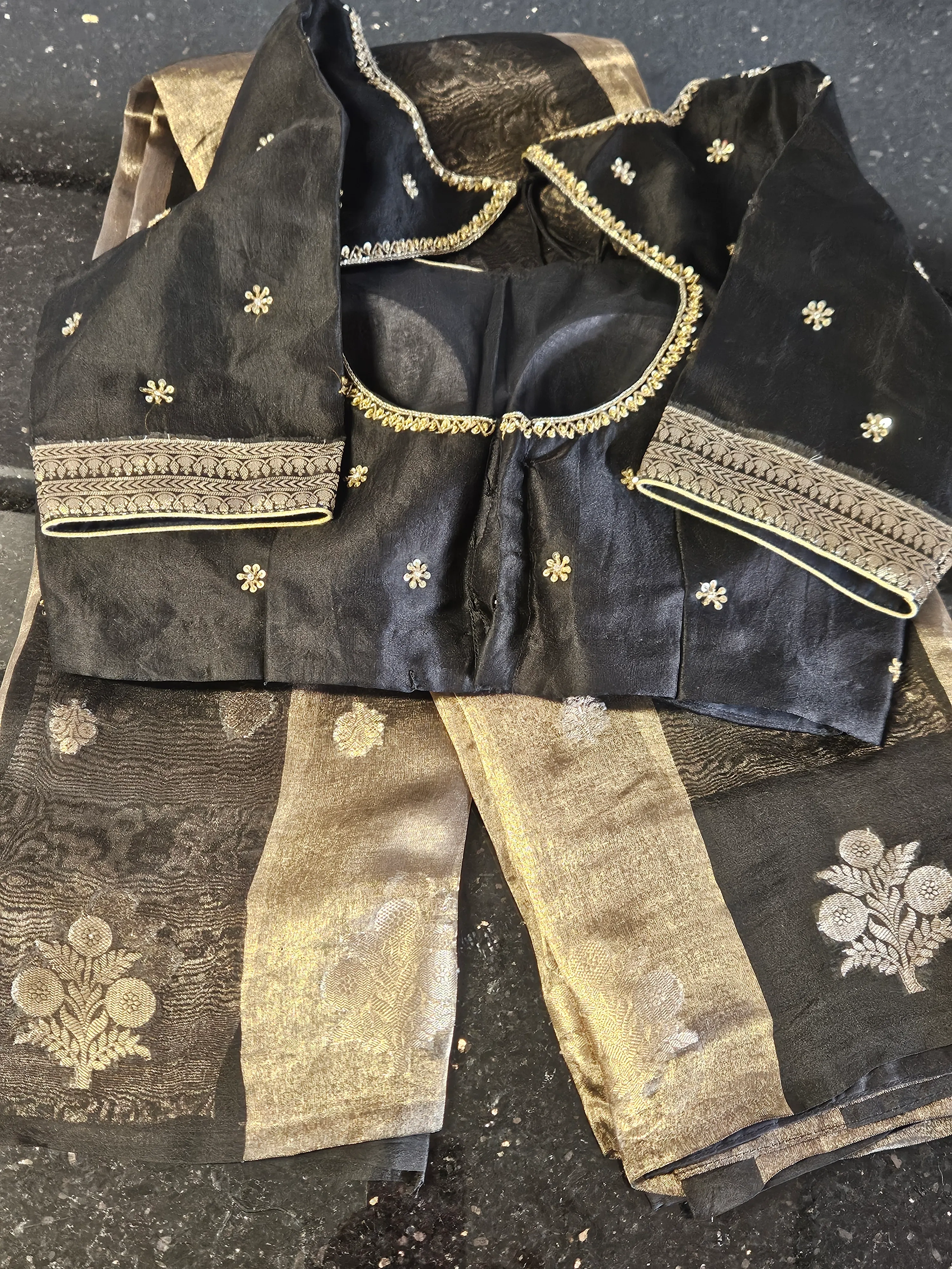 Pure Banarasi Kora Tissue saree in gold and silver zari with floral motifs, paired with a black embroidered blouse.