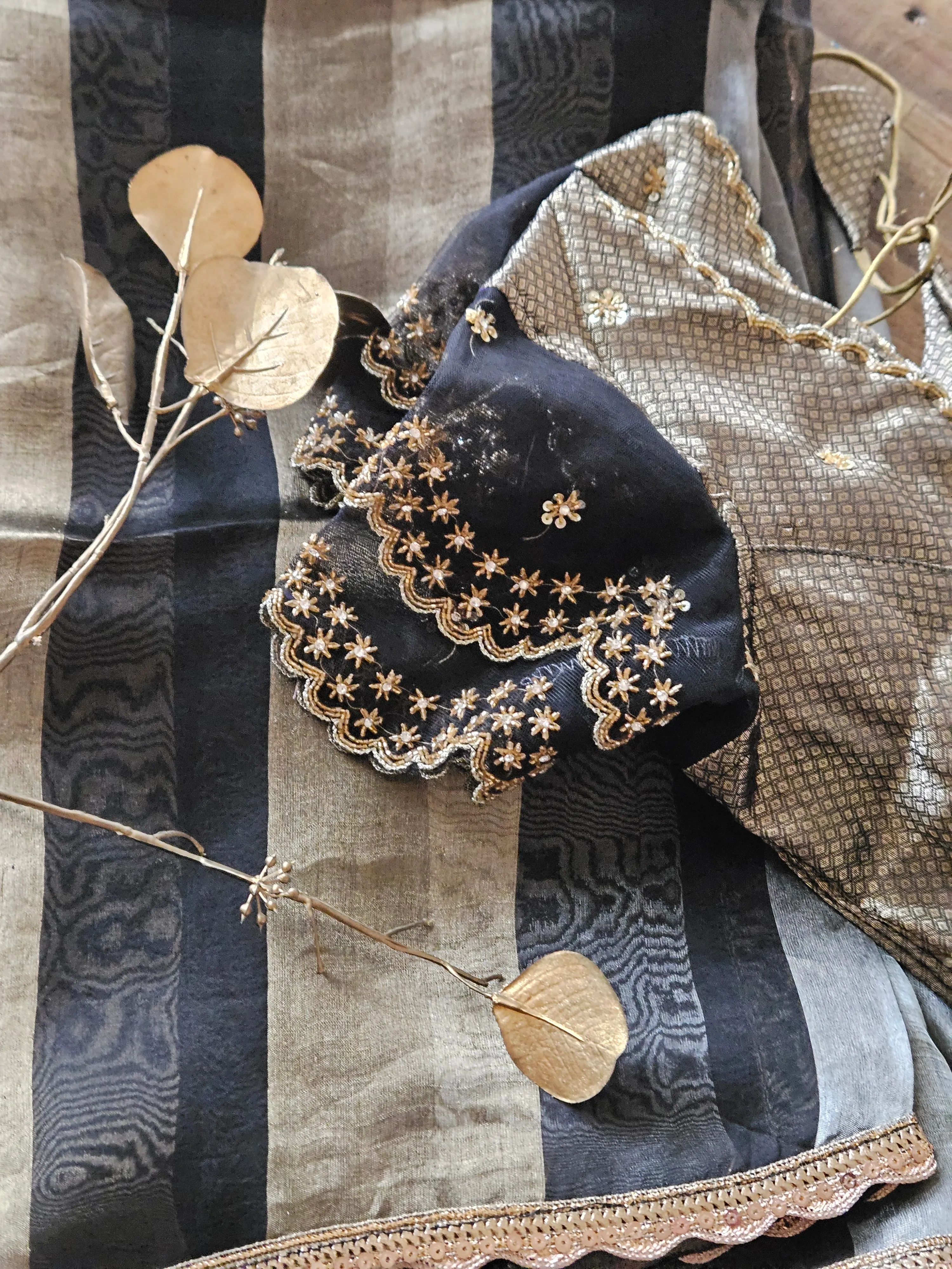Pure Banarasi Kora tissue saree in pastel gold and black with handwoven gold and silver zari, floral embroidery, and scalloped border.