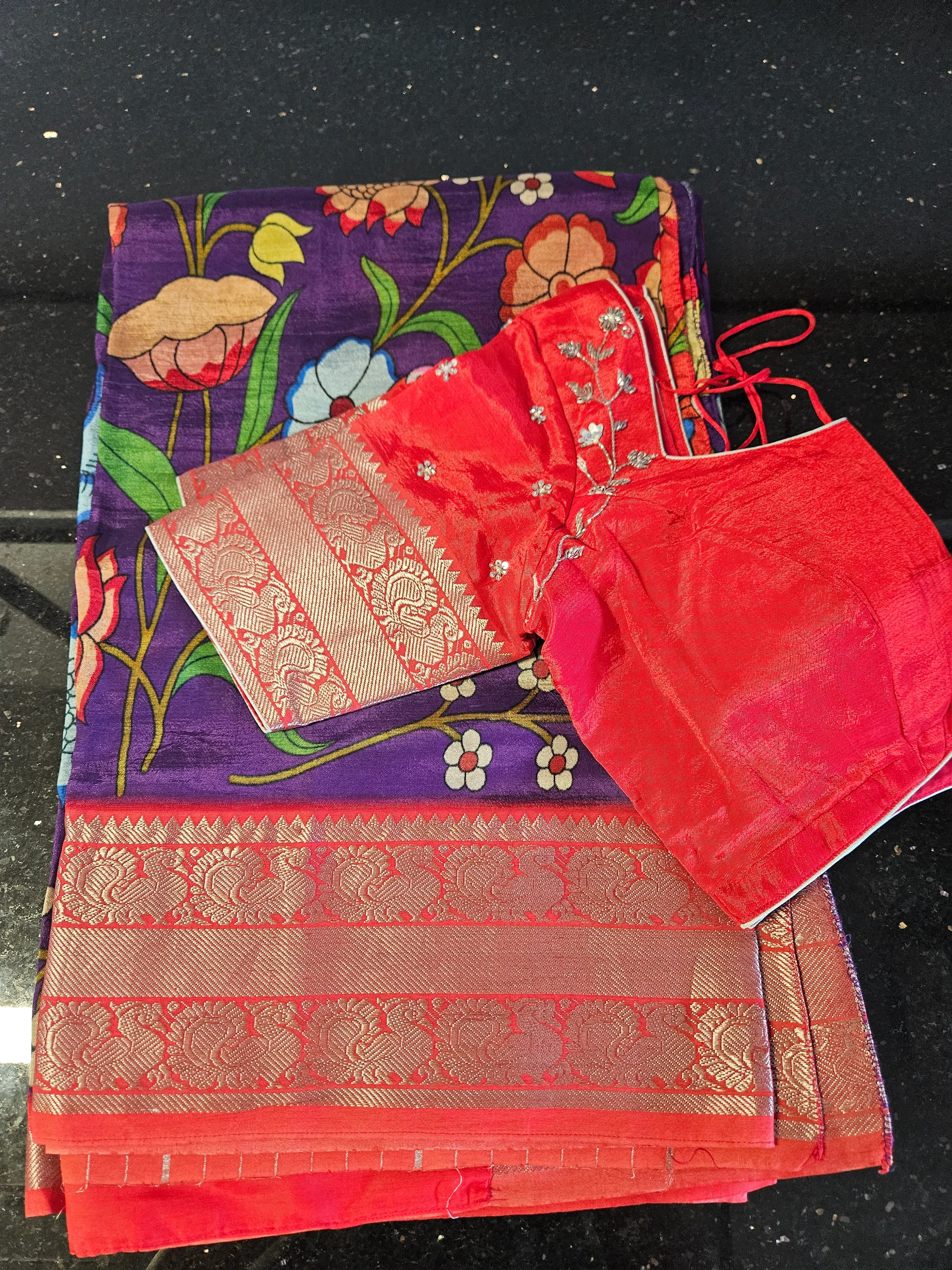 Handwoven Mangalagiri silk pattu saree with vibrant floral patterns, rich purple base, golden zari border, and red blouse piece