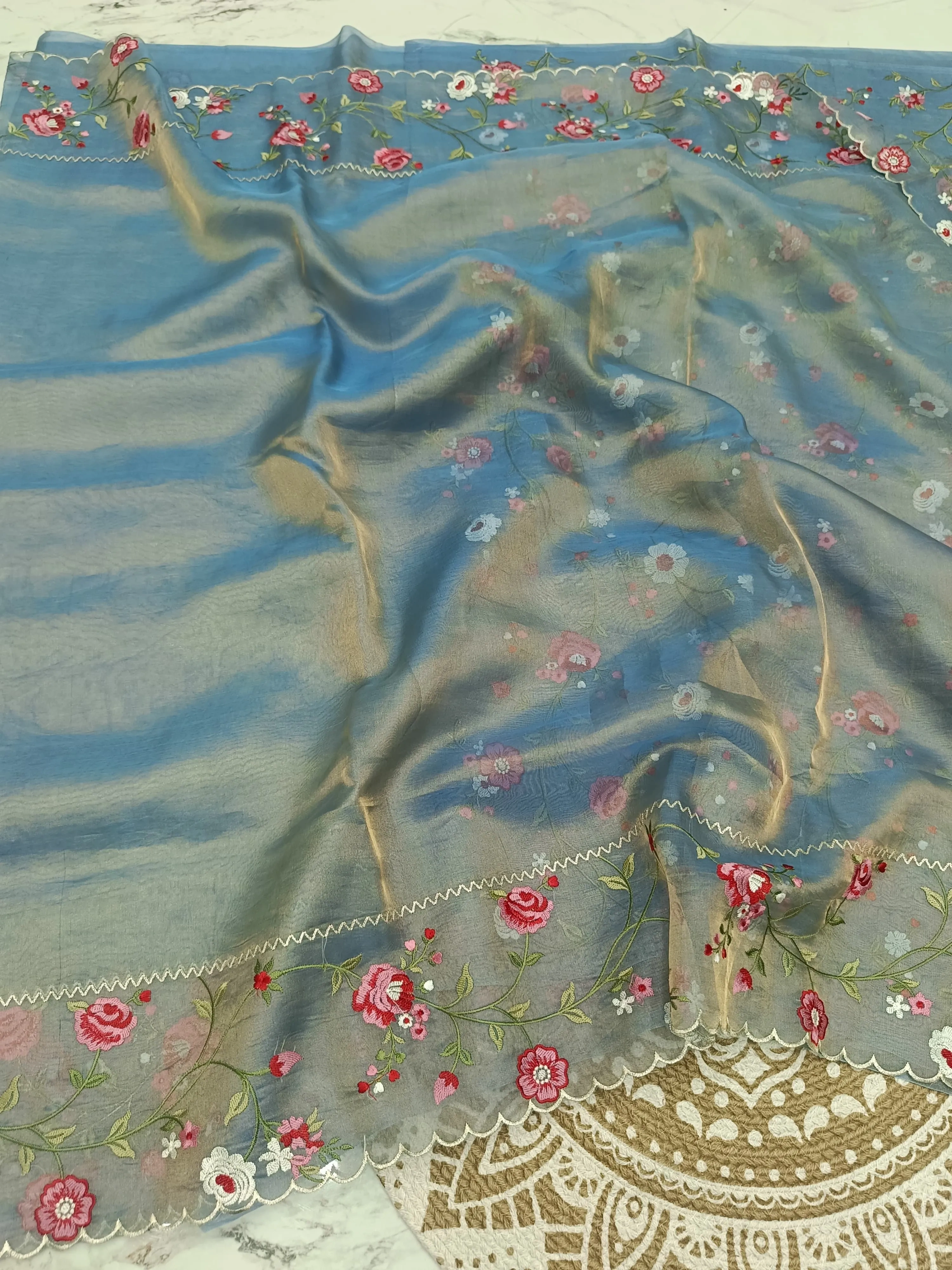 Handwoven Banarasi tissue silk saree in soft blue with gold and silver zari, floral embroidery, and scalloped border