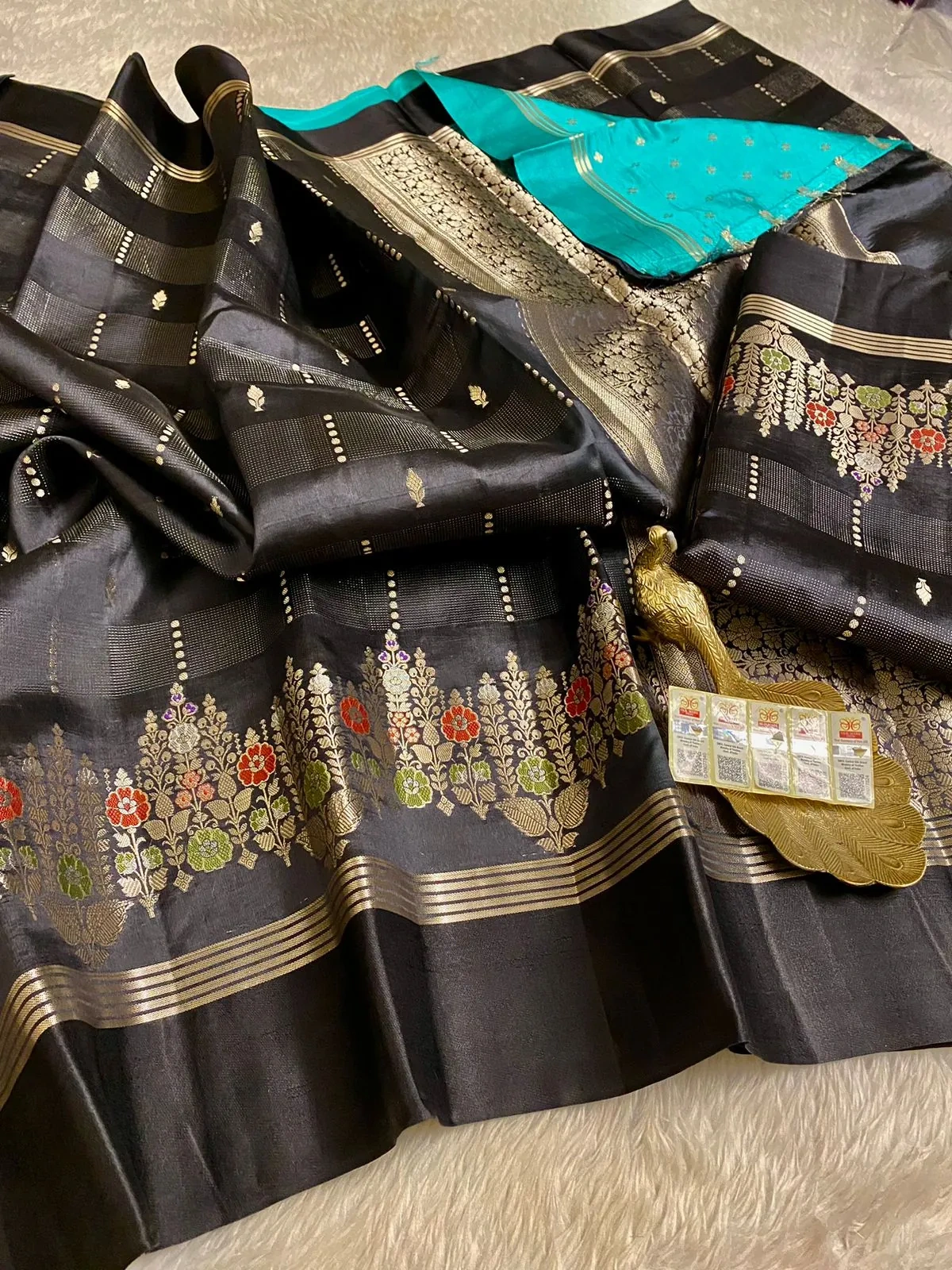Pure handloom raw mango yellow silk pattu saree with black base, gold zari floral motifs, and contrasting blue pallu.