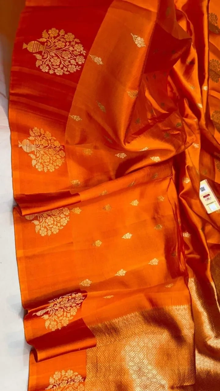 Handwoven raw mango yellow pure silk pattu saree with gold zari motifs and rich red-orange border, ideal for weddings.