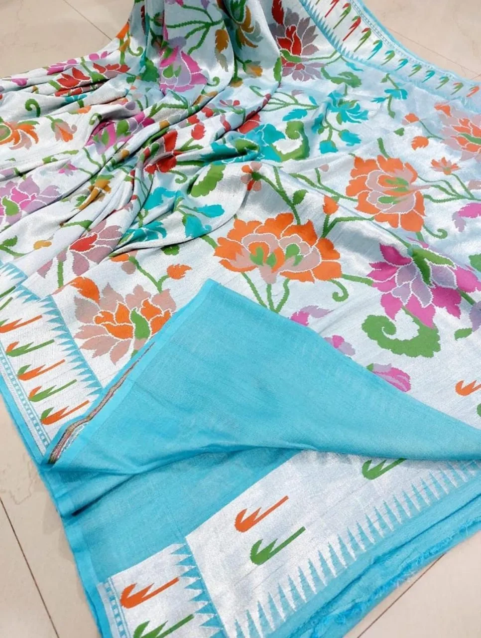 Pure Tussar silk georgette saree in beige with vibrant multicolor floral patterns and a contrasting sky blue border.