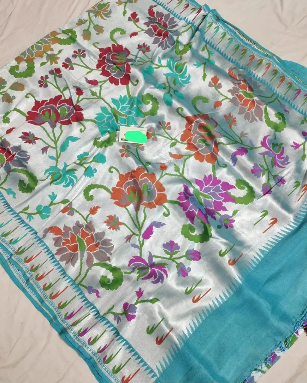 Pure Tussar silk georgette saree in beige with vibrant multicolor floral embroidery and turquoise blue border, ideal for weddings.