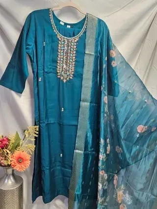 Gold pure Dola silk kurti set featuring intricate embroidery, paired with a sheer floral embroidered dupatta, festive ethnic wear.