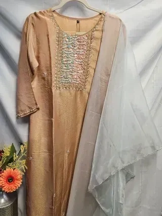 Handcrafted pure tissue silk gown in gold with pastel embroidered yoke, paired with a sheer light dupatta, ideal for weddings.