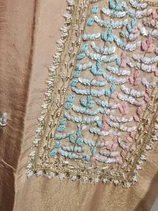Handcrafted pure tissue silk gown in gold with intricate pastel blue and pink thread embroidery, ideal for weddings.