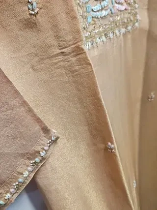 Handcrafted pure tissue silk gown in gold with delicate pastel embroidery, ideal for Indian weddings and festivals.