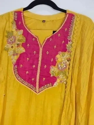 Mustard yellow Chanderi silk suit with gold embroidery, hot pink yoke, floral accents, and festive ethnic detailing