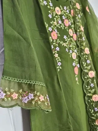 Olive green muslin lehenga with delicate floral embroidery in pink, peach, and lavender, scalloped sleeve detailing