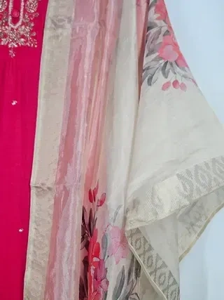 Ivory muslin Anarkali gown with floral prints and subtle gold border, ideal for weddings and festive occasions.