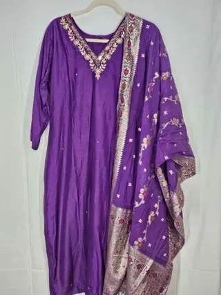 Jewel-toned purple pure Dola silk gown with intricate floral embroidery and matching embroidered dupatta, ideal for weddings.
