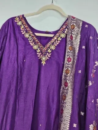 Jewel-toned purple pure Dola silk gown with gold floral embroidery and matching embroidered dupatta, ideal for weddings.