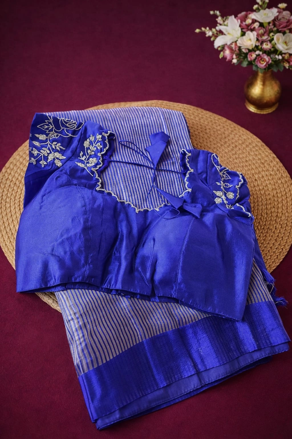 Royal blue Banarasi Kora tissue silk saree with silver zari stripes, paired with an embroidered blouse, displayed on a mat.