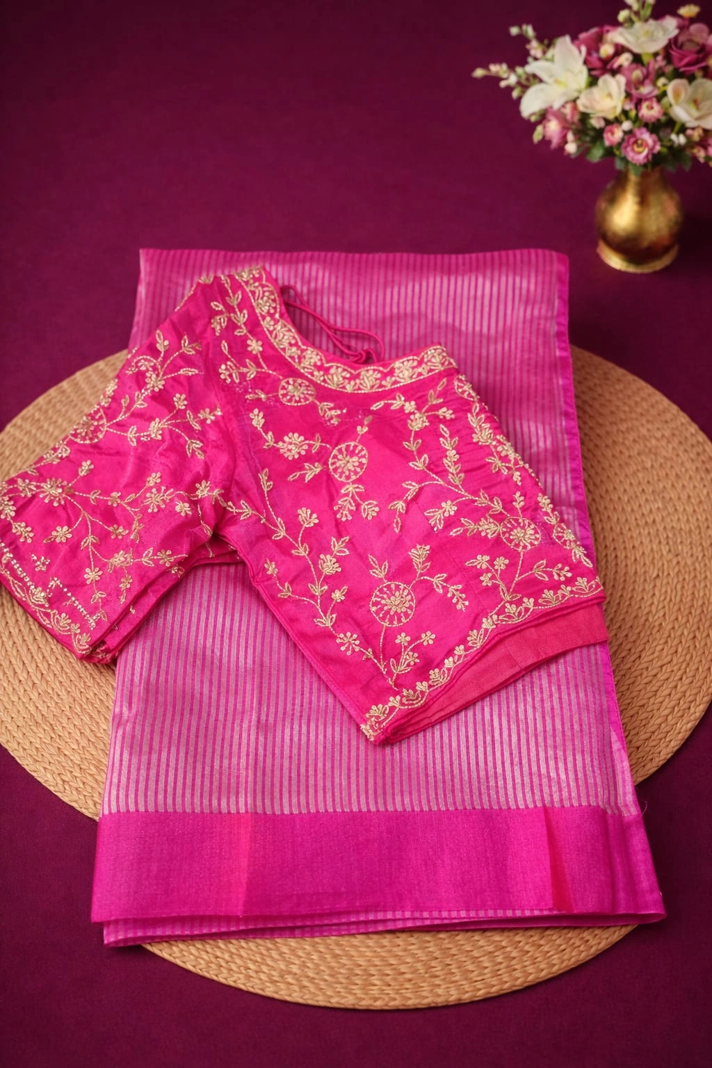 Handwoven Banarasi Kora tissue silk saree in vibrant pink with gold zari border, paired with an embroidered blouse.