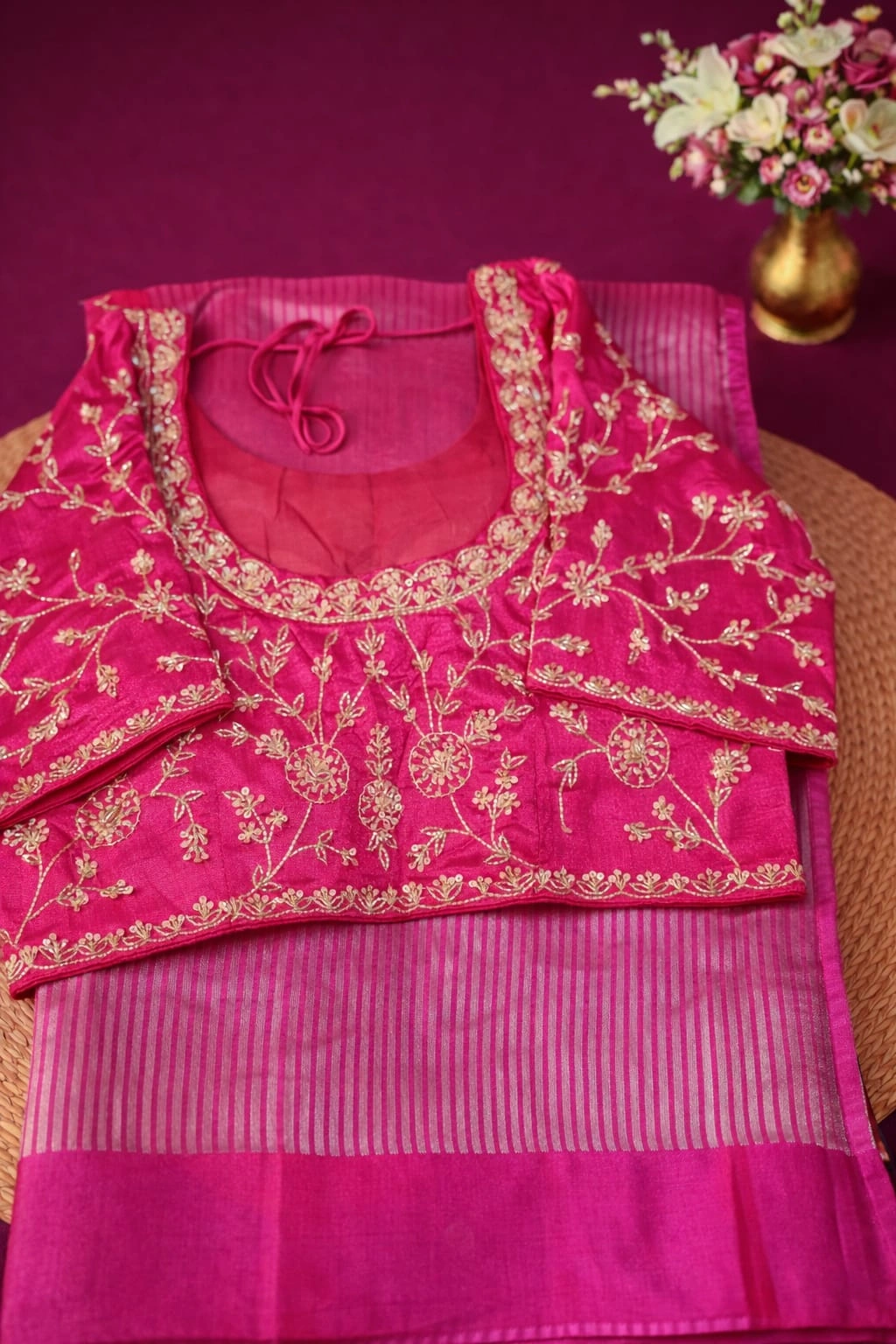 Handwoven Banarasi Kora tissue silk saree in vibrant pink with gold zari border, paired with an embroidered blouse.